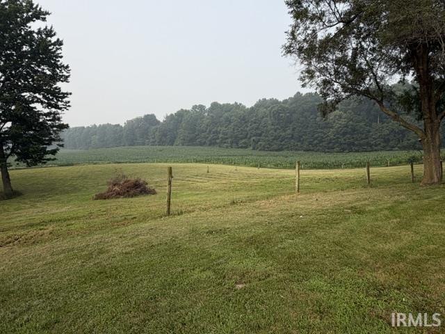 Expansive grass lawn bordered by mature trees and a distant field