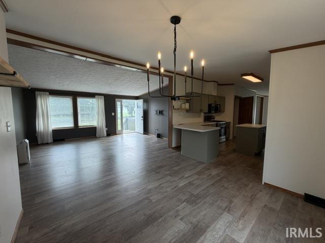 Open-concept living space featuring wood-finish flooring, a contemporary chandelier, and a kitchen with gray cabinetry, light countertops, and stainless steel appliances