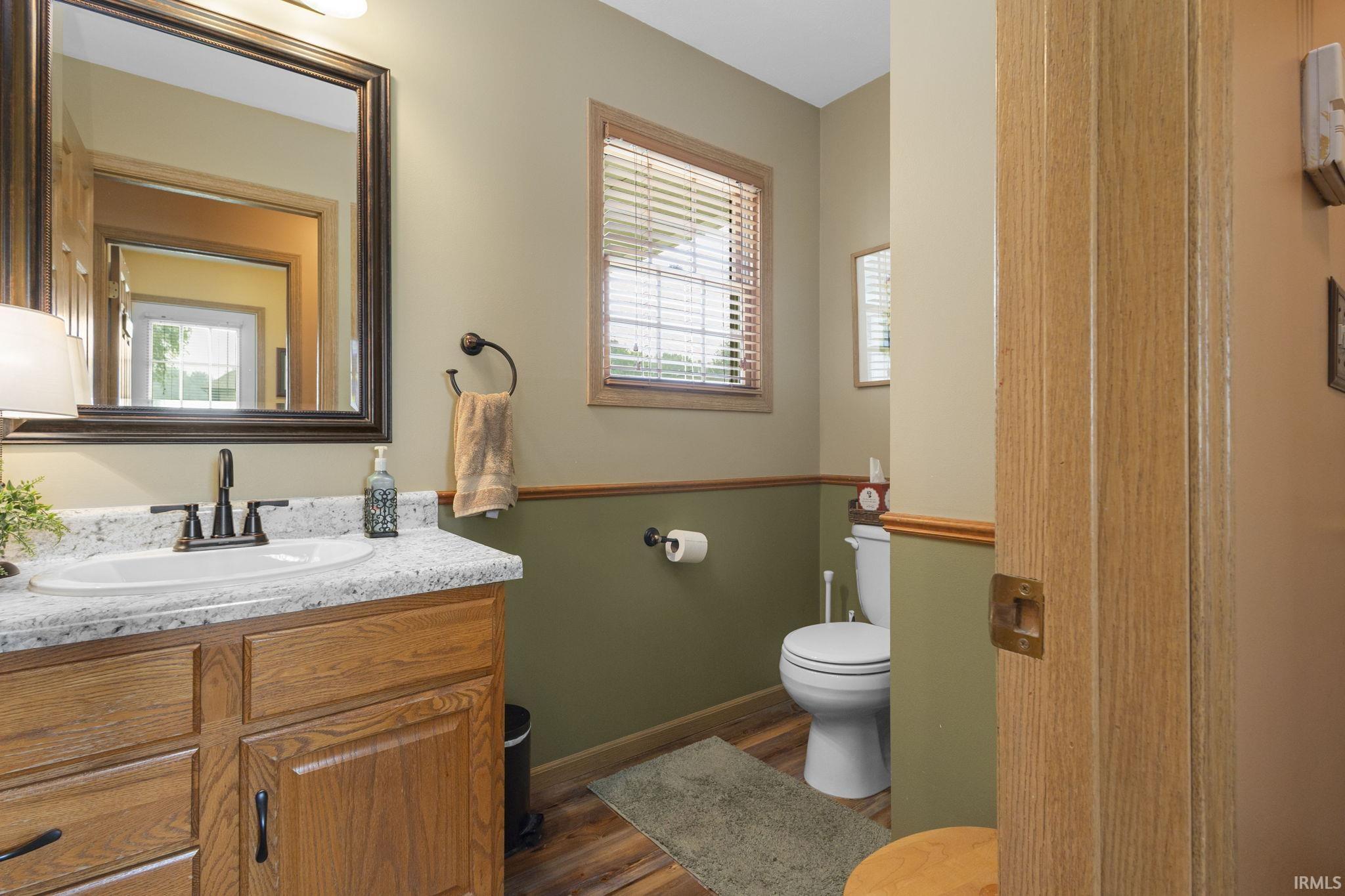 Bathroom featuring a wood-finish vanity with a light speckled countertop, undermount sink, and black faucet