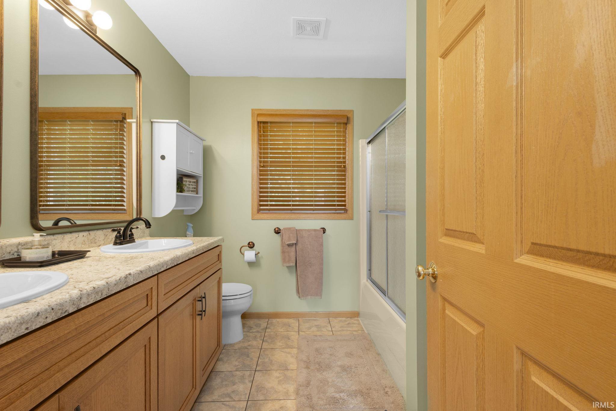 Bathroom featuring a double vanity with light-toned countertops, wood cabinetry, and dual sinks
