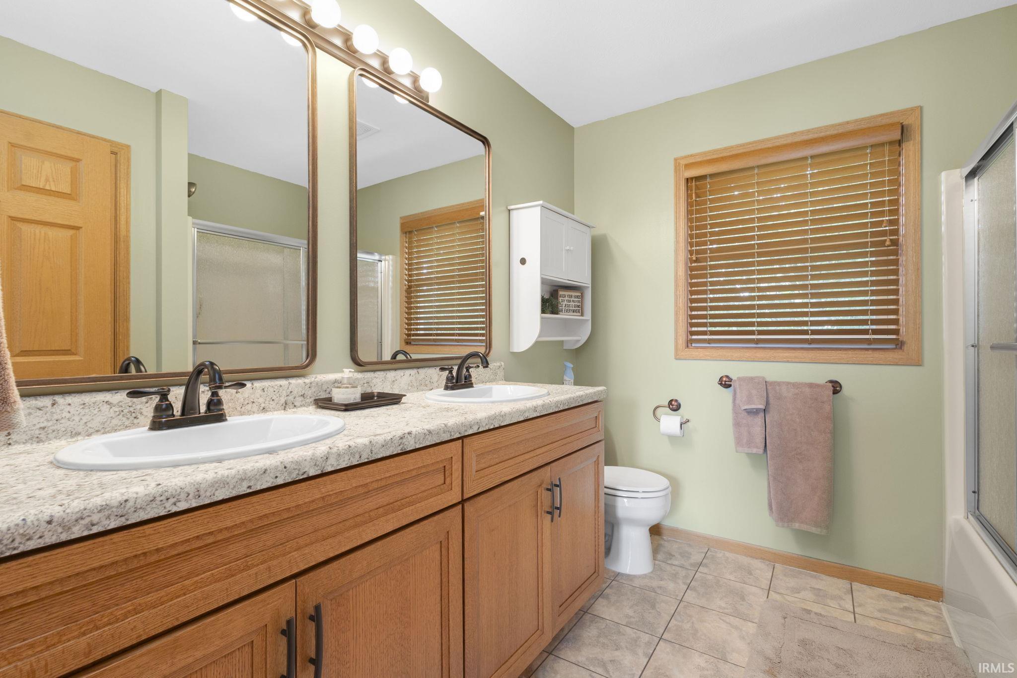 Double vanity with undermount sinks, speckled countertop, and wood-finish cabinetry
