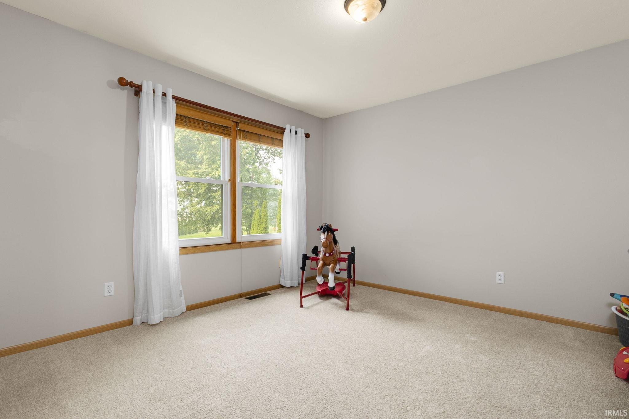 Room featuring a neutral wall color, light-toned carpet, and a double window with wood trim