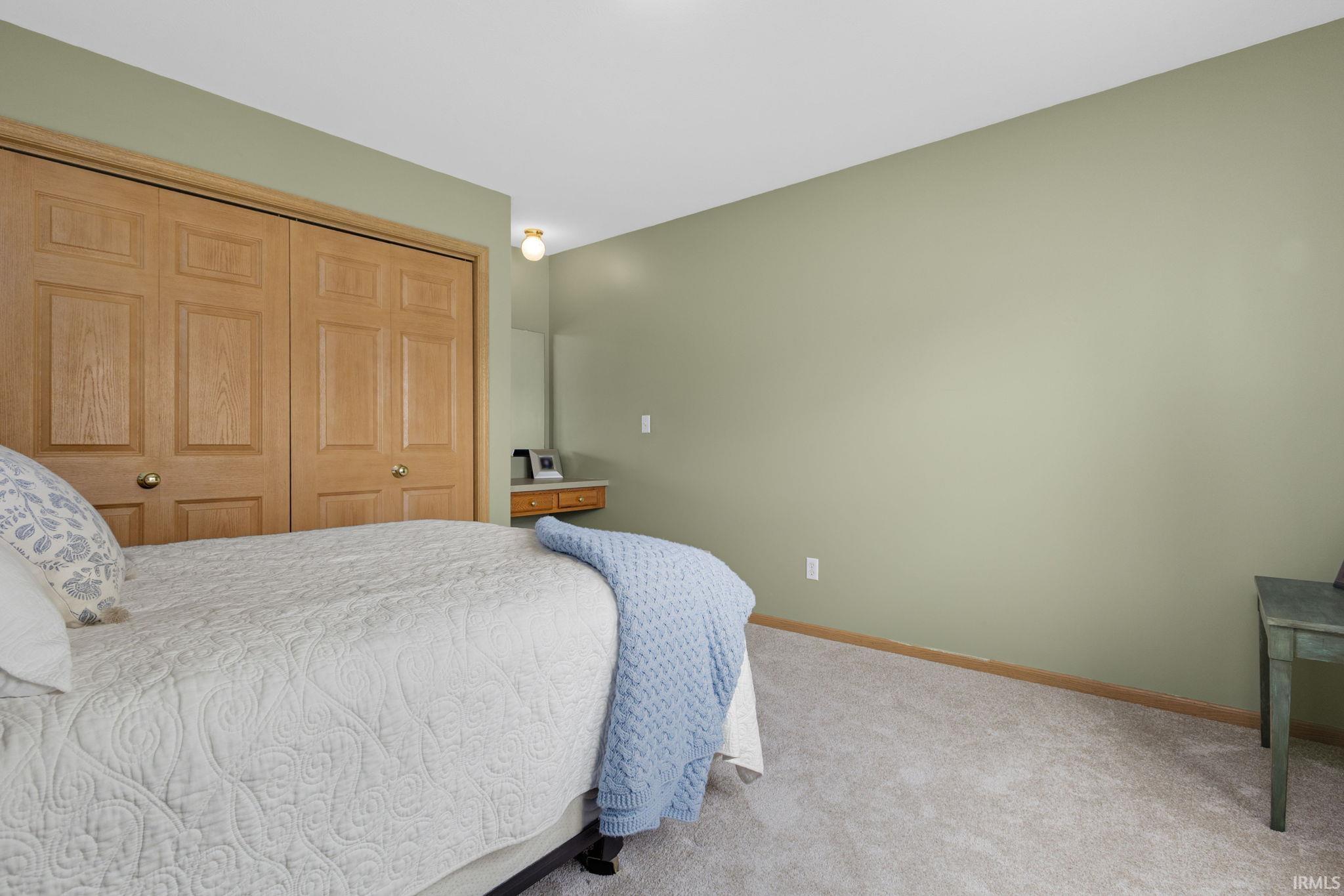 Bedroom with light green walls and light-colored carpet flooring