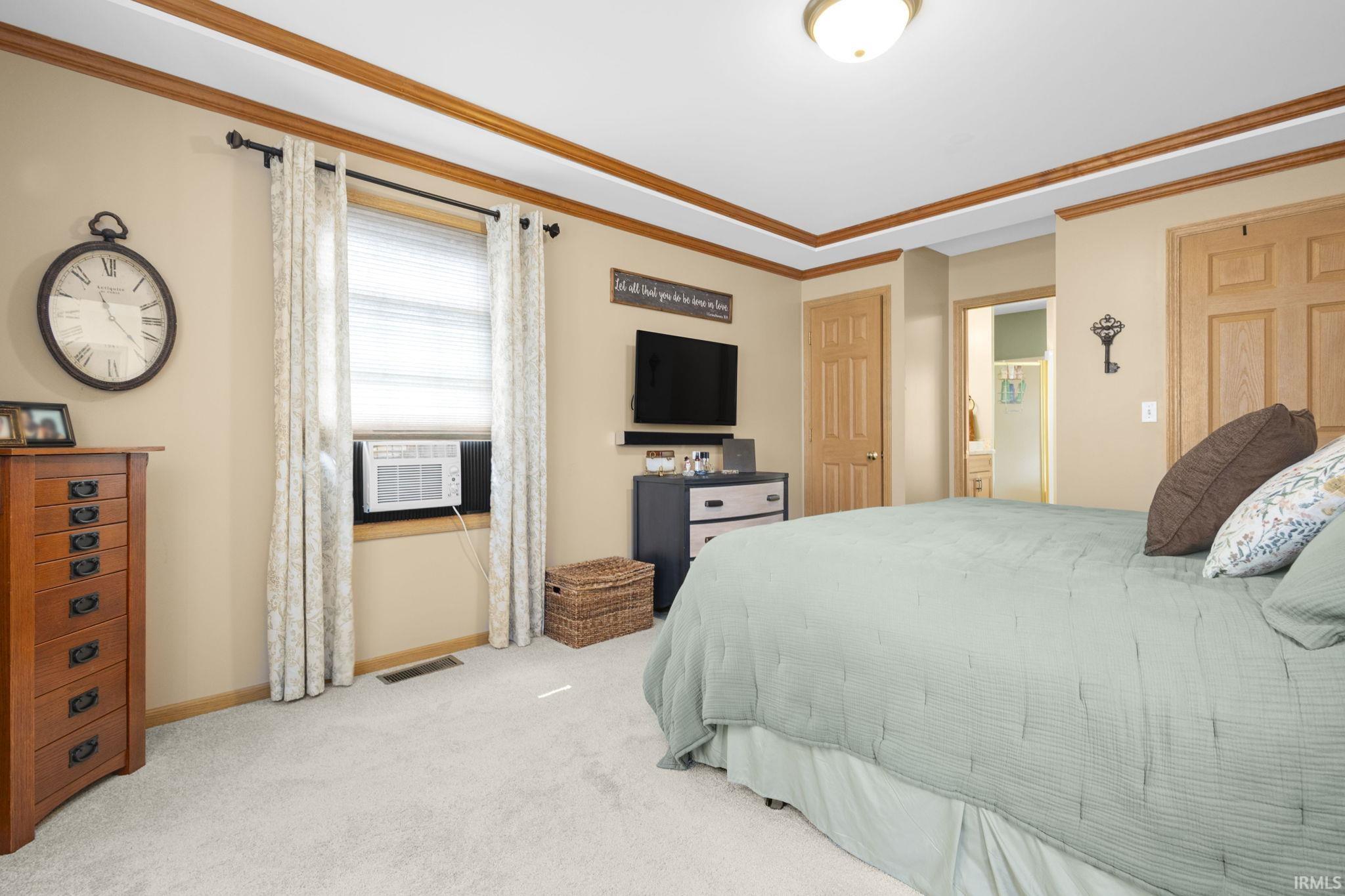 Carpeted room featuring a ceiling light fixture, crown molding, and a window