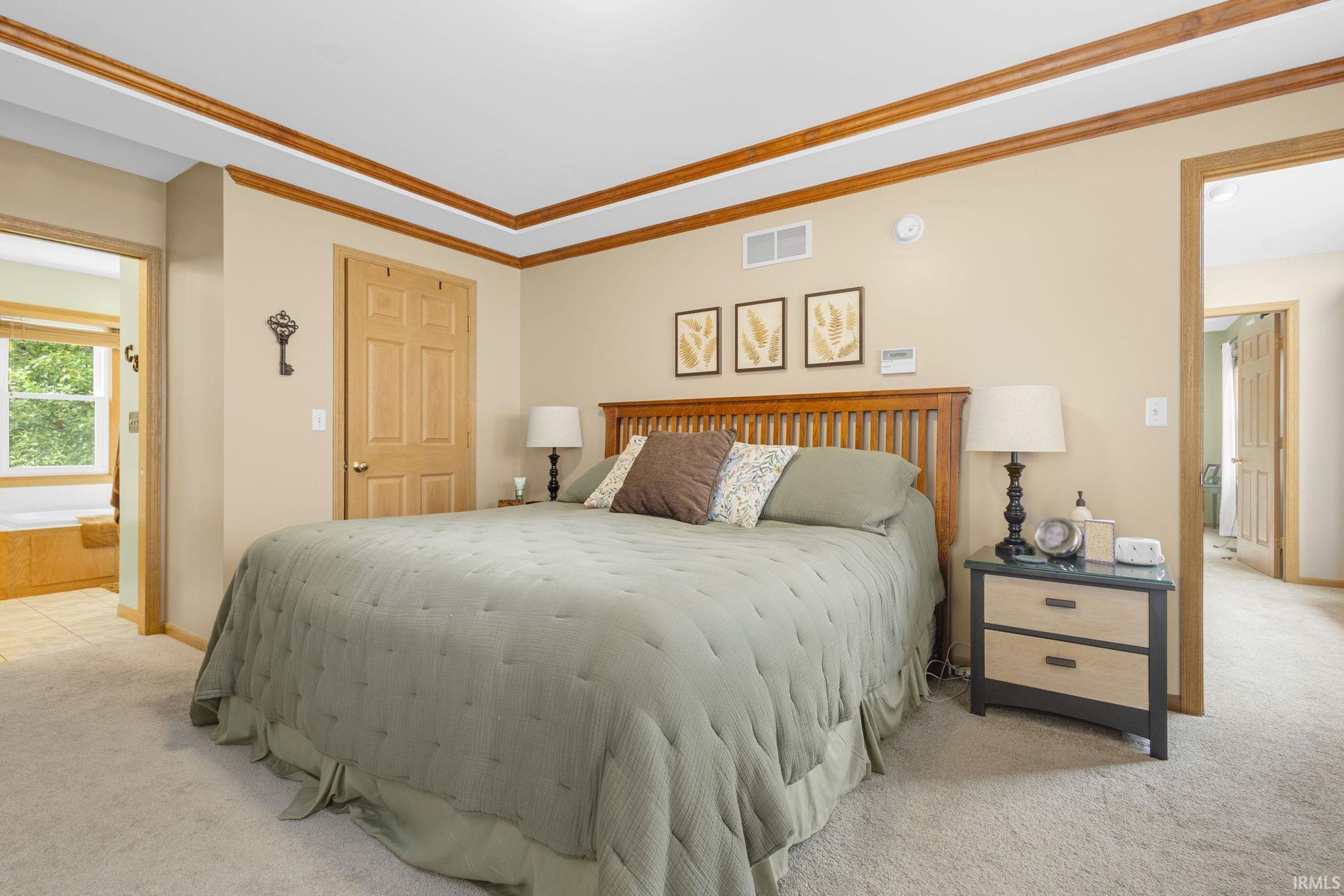 Carpeted bedroom with a tray ceiling featuring wood trim accents