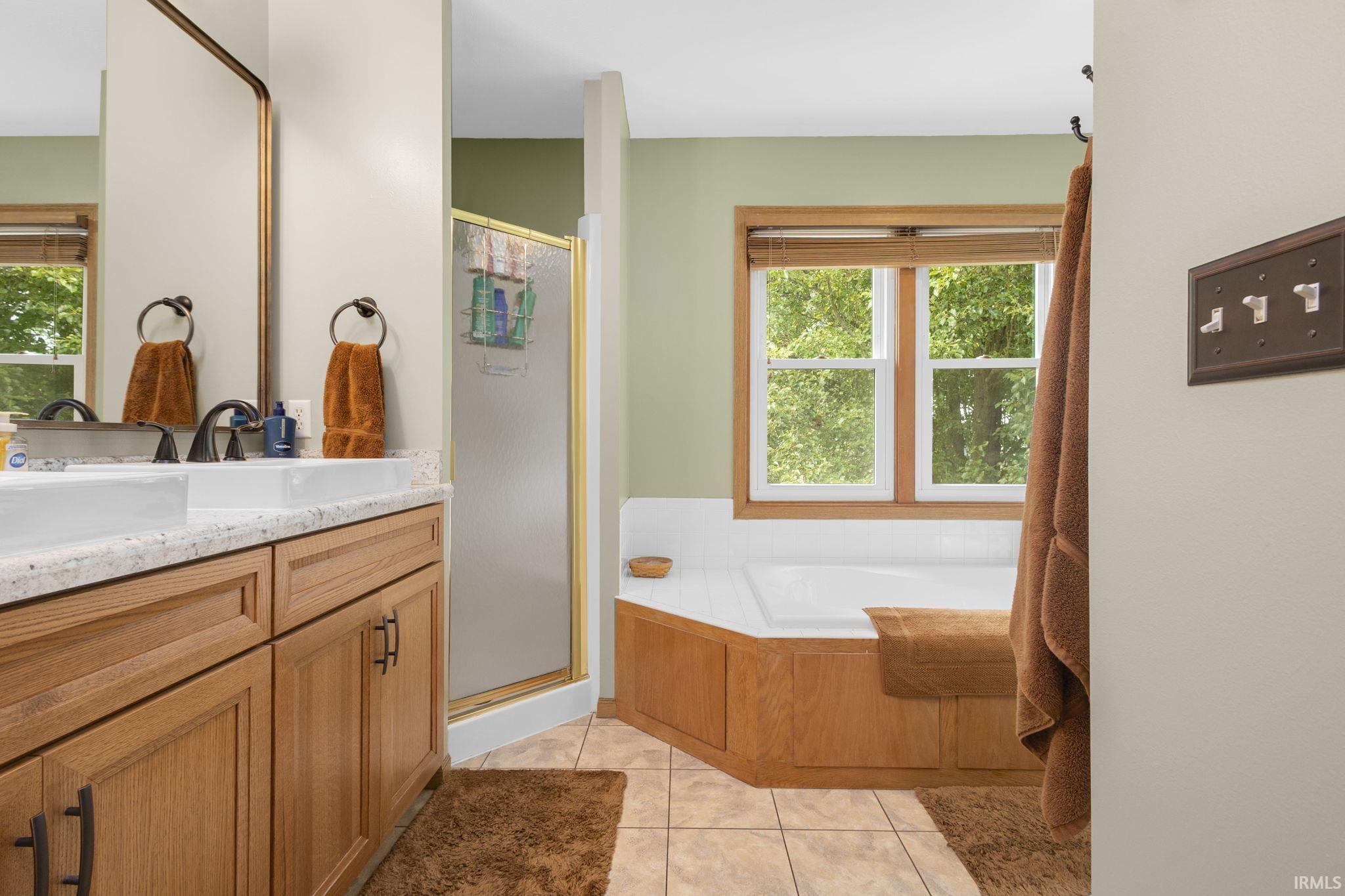 Dual vanity with a light-toned countertop, wood-finish cabinetry, and oil-rubbed bronze hardware