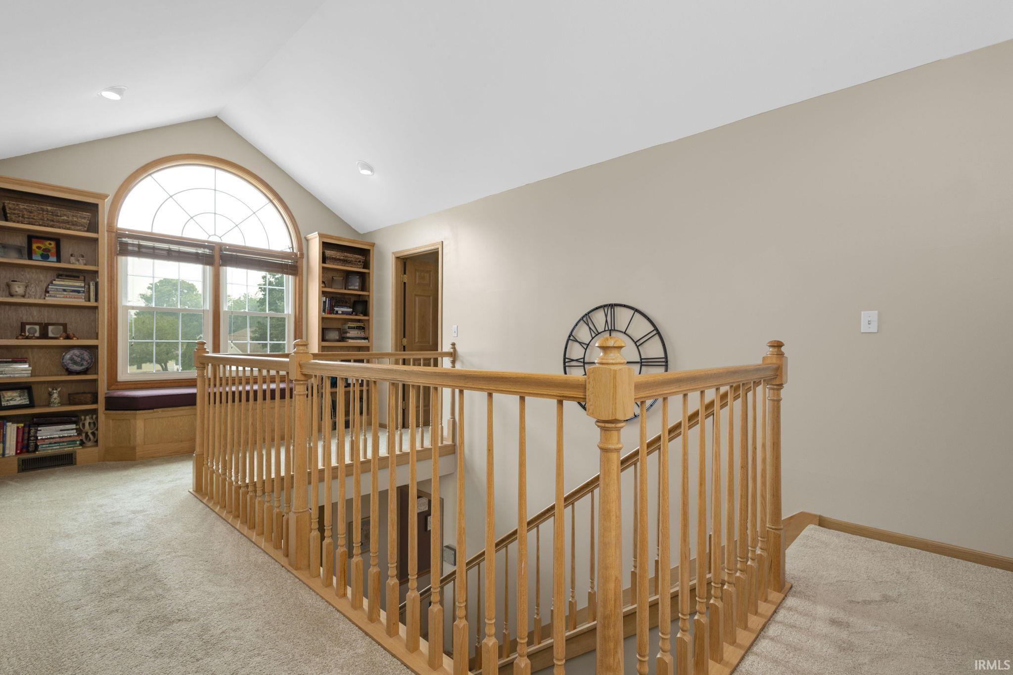 Open loft area featuring an arched window, integrated window seating, and built-in shelving