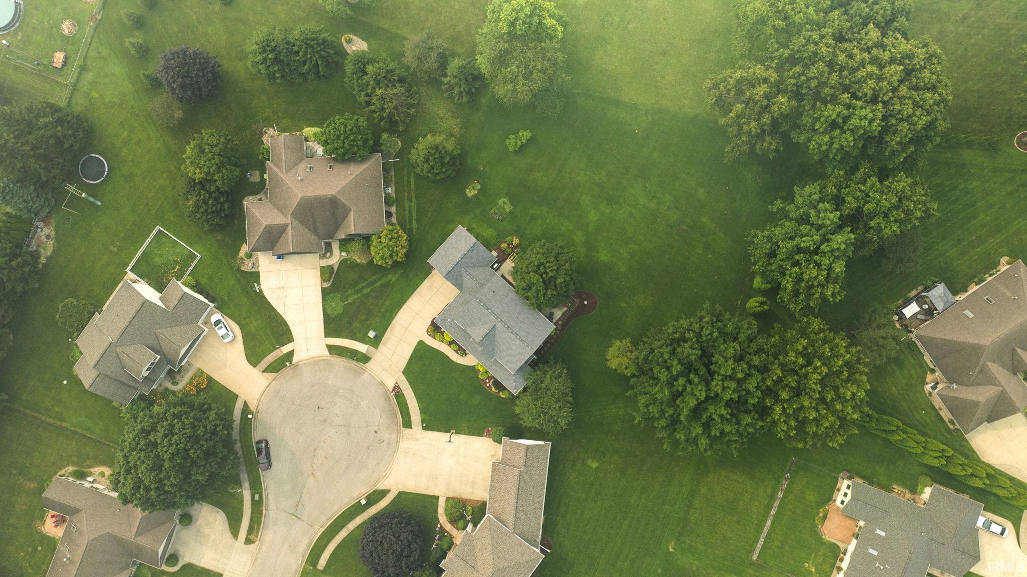 Cul-de-sac setting with multiple residential properties featuring expansive green lawns and mature trees