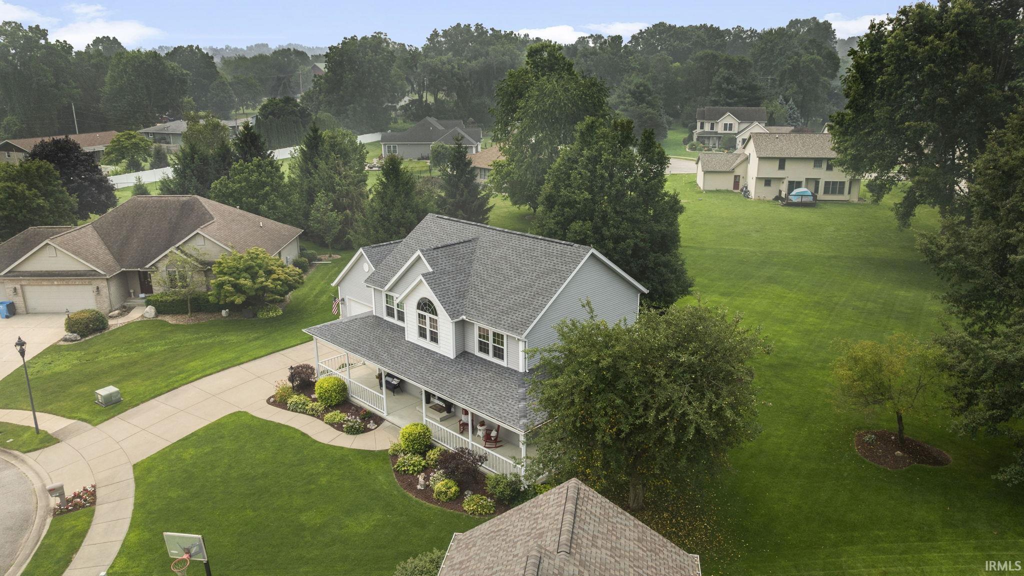 Two-story residence featuring a covered front porch, light gray siding, and an arched window detail