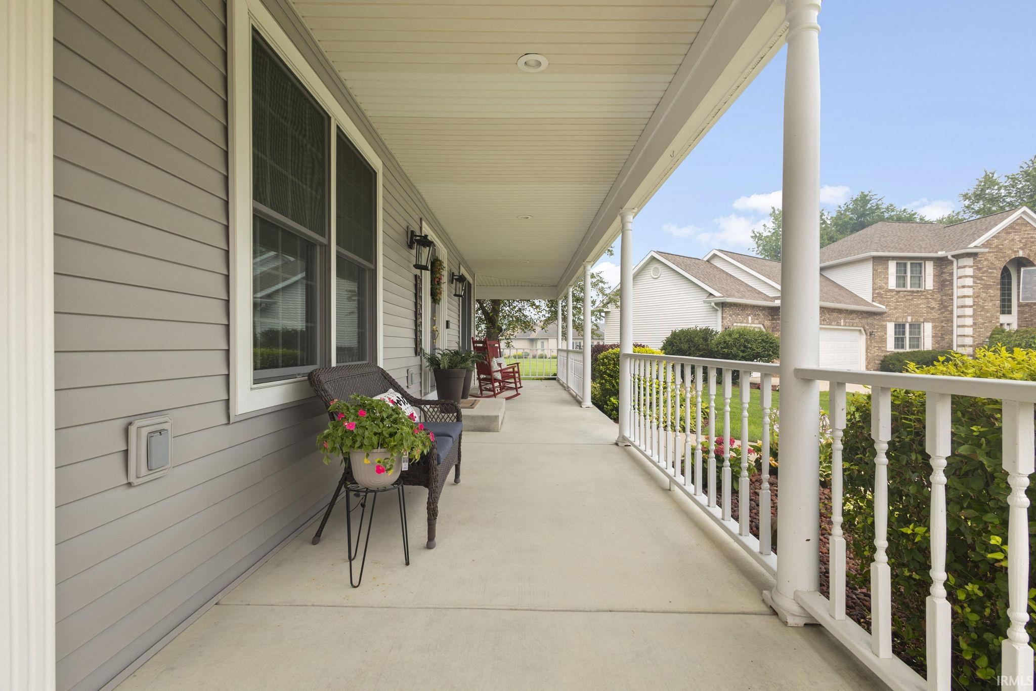 Expansive covered porch with white railing, gray horizontal siding, and multiple windows