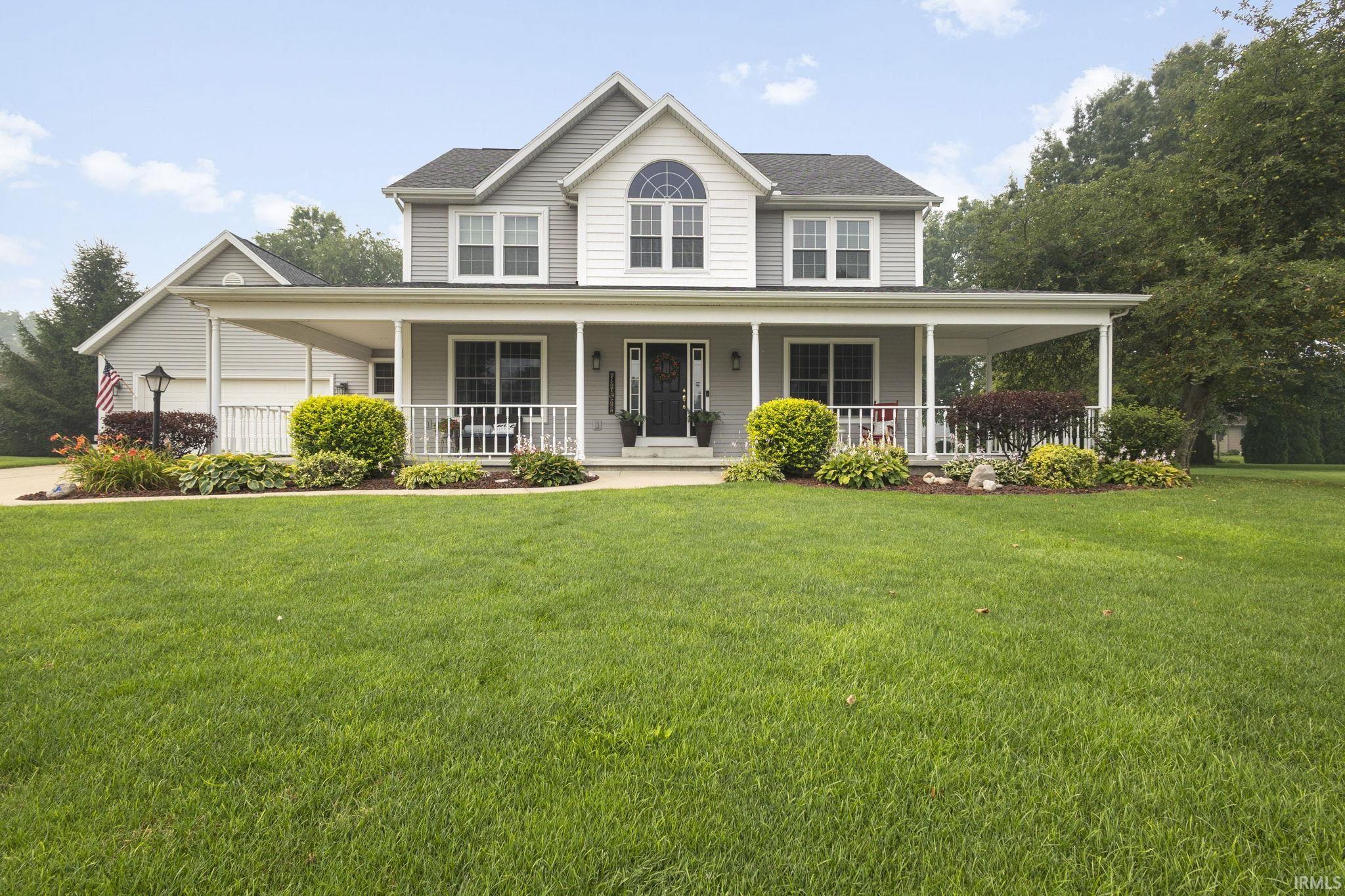 Two-story home featuring light gray siding, white trim, and a prominent covered porch spanning the front facade