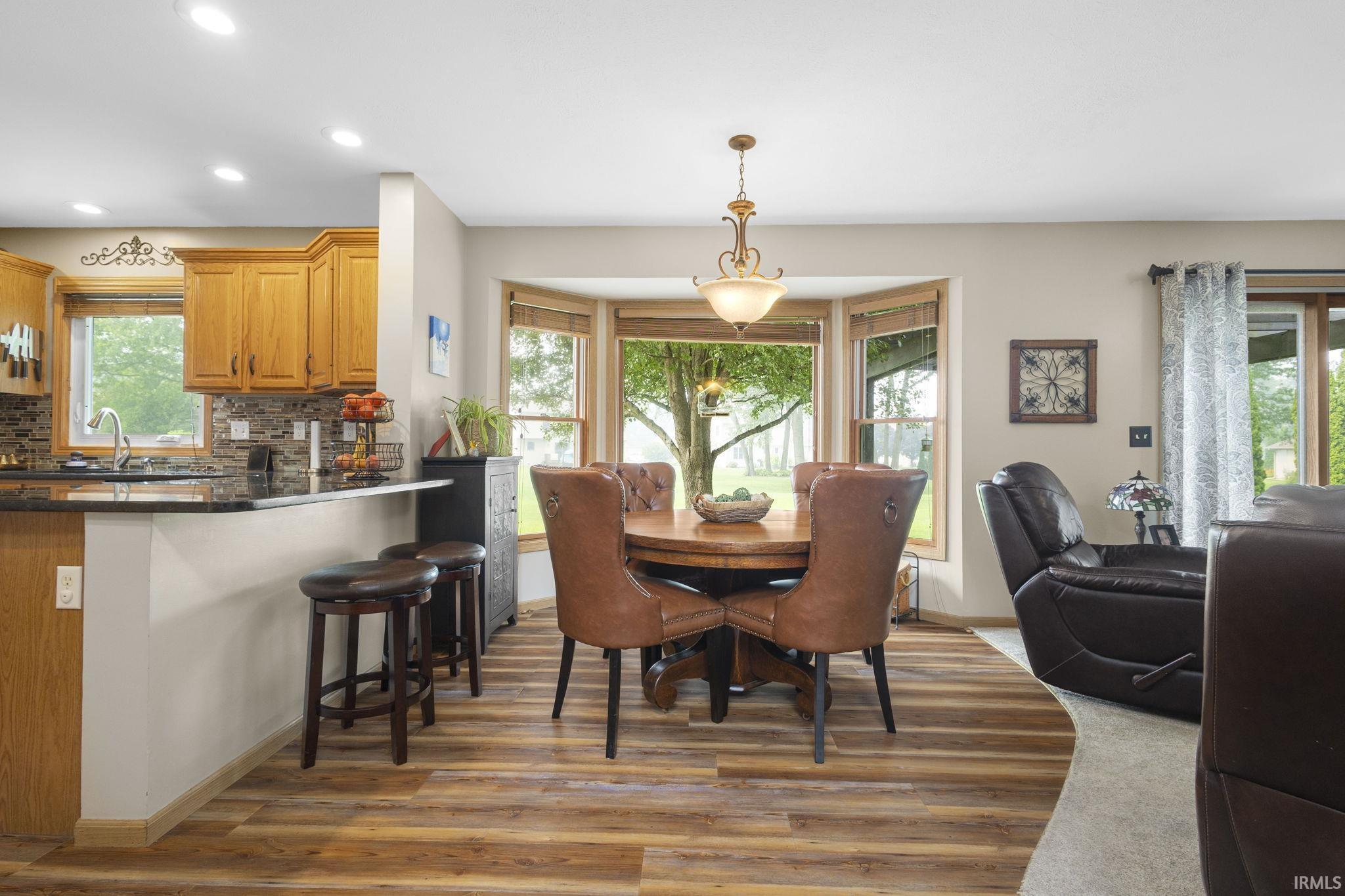 Dining area featuring bay windows, a chandelier, and wood-finish flooring