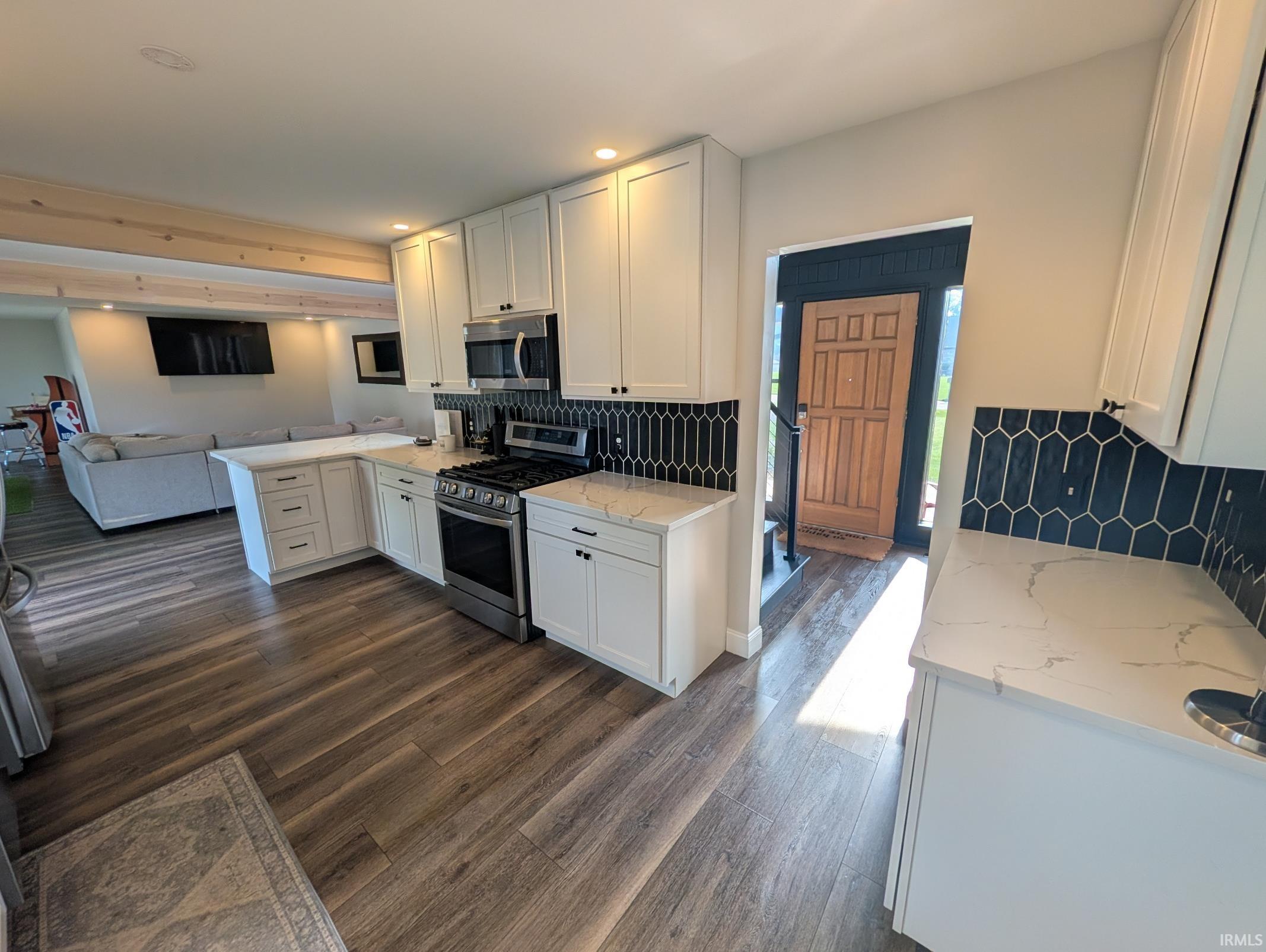 Modern kitchen featuring white shaker cabinetry, stainless steel appliances, and quartz countertops
