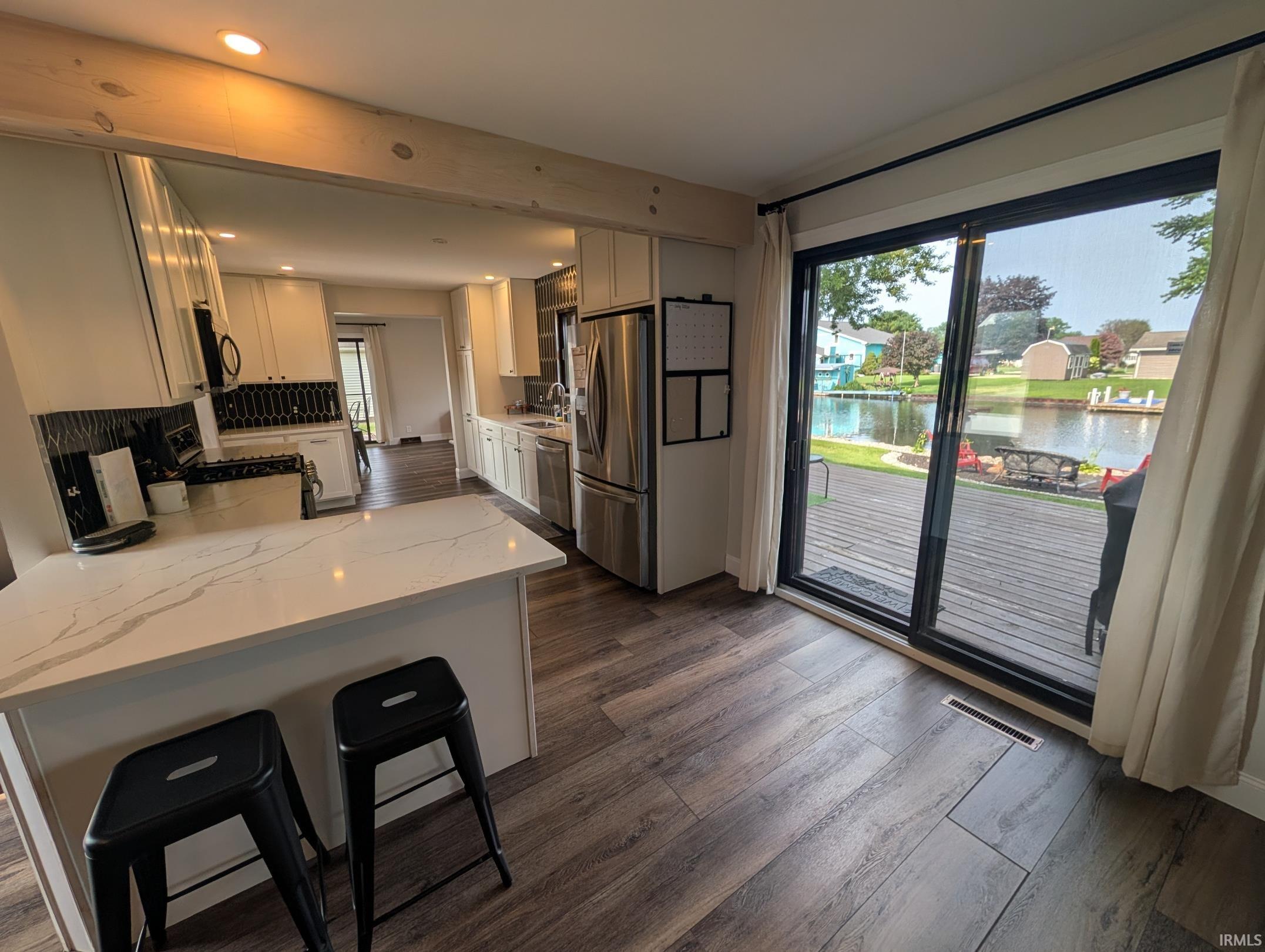Kitchen featuring an island with a light-toned countertop, stainless steel appliances, and wood-finish flooring