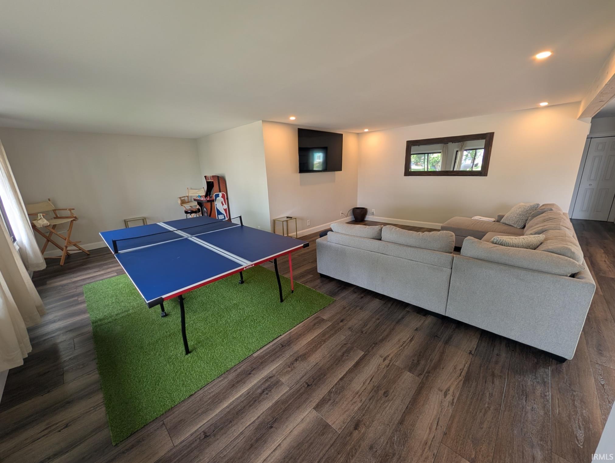 Spacious room featuring wood-finish flooring and recessed lighting
