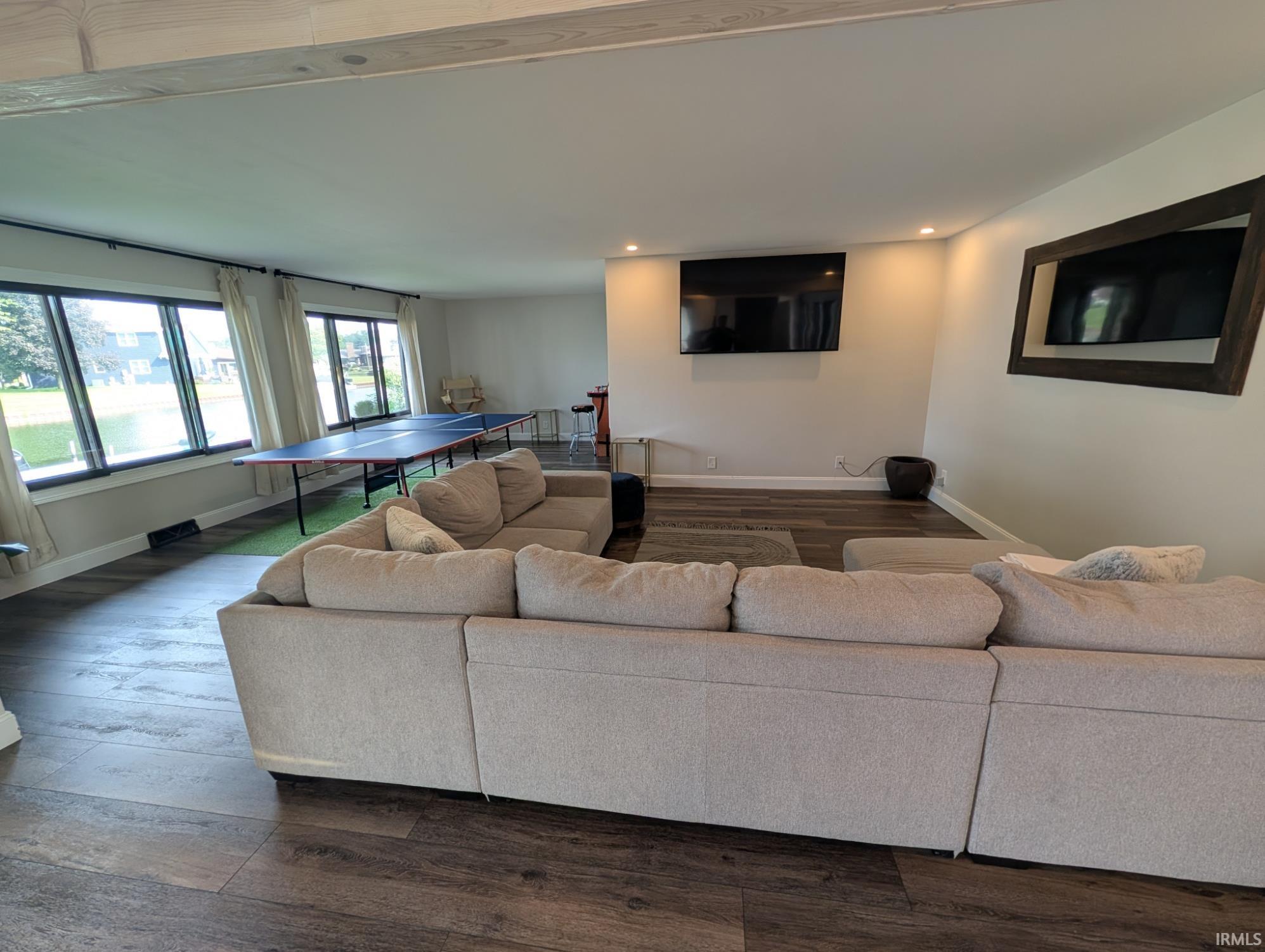 Spacious living area featuring expansive windows, wood-finish flooring, recessed lighting, and light-toned walls
