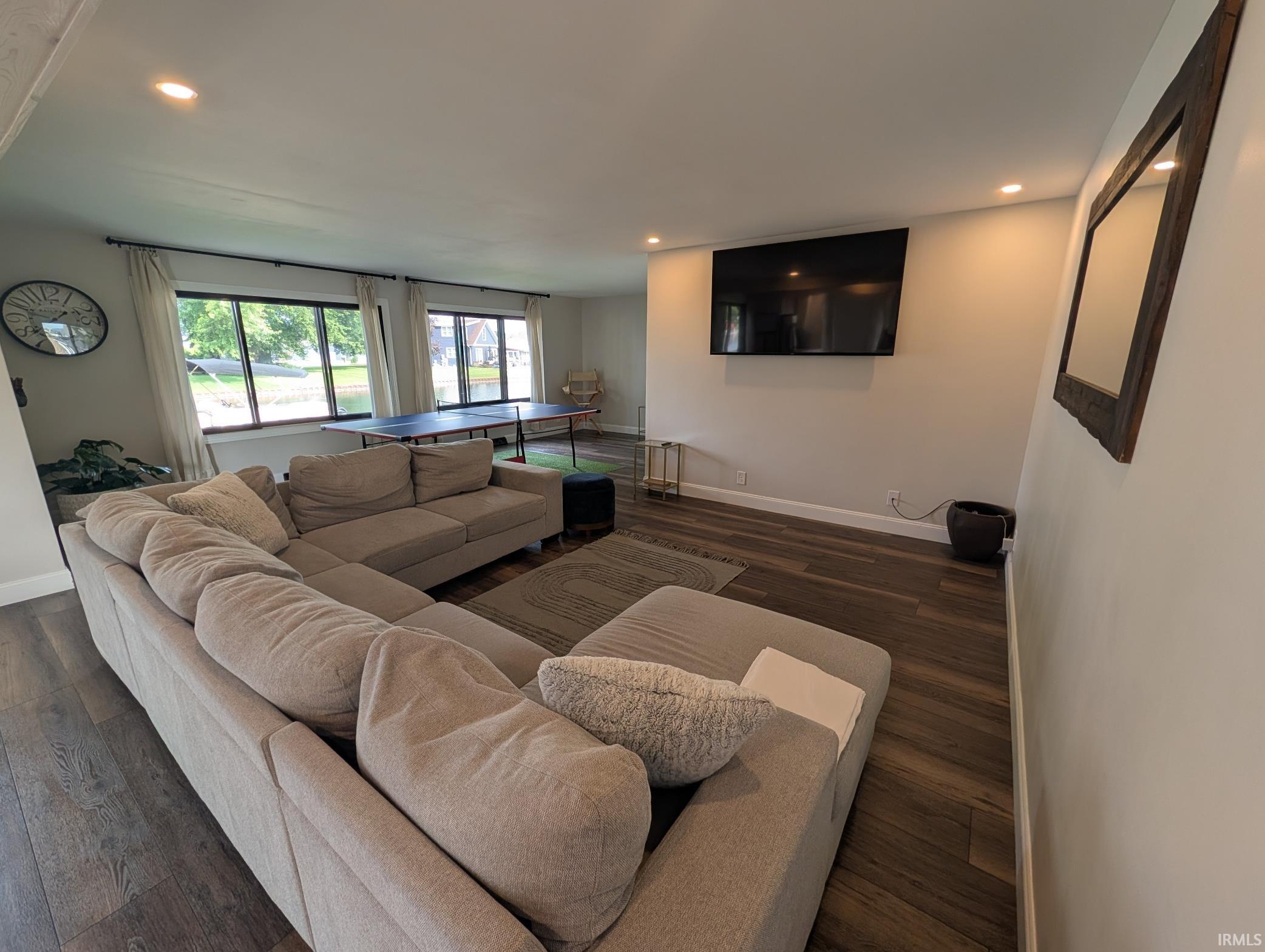 Spacious living area featuring wood-finish flooring, recessed lighting, and white baseboards