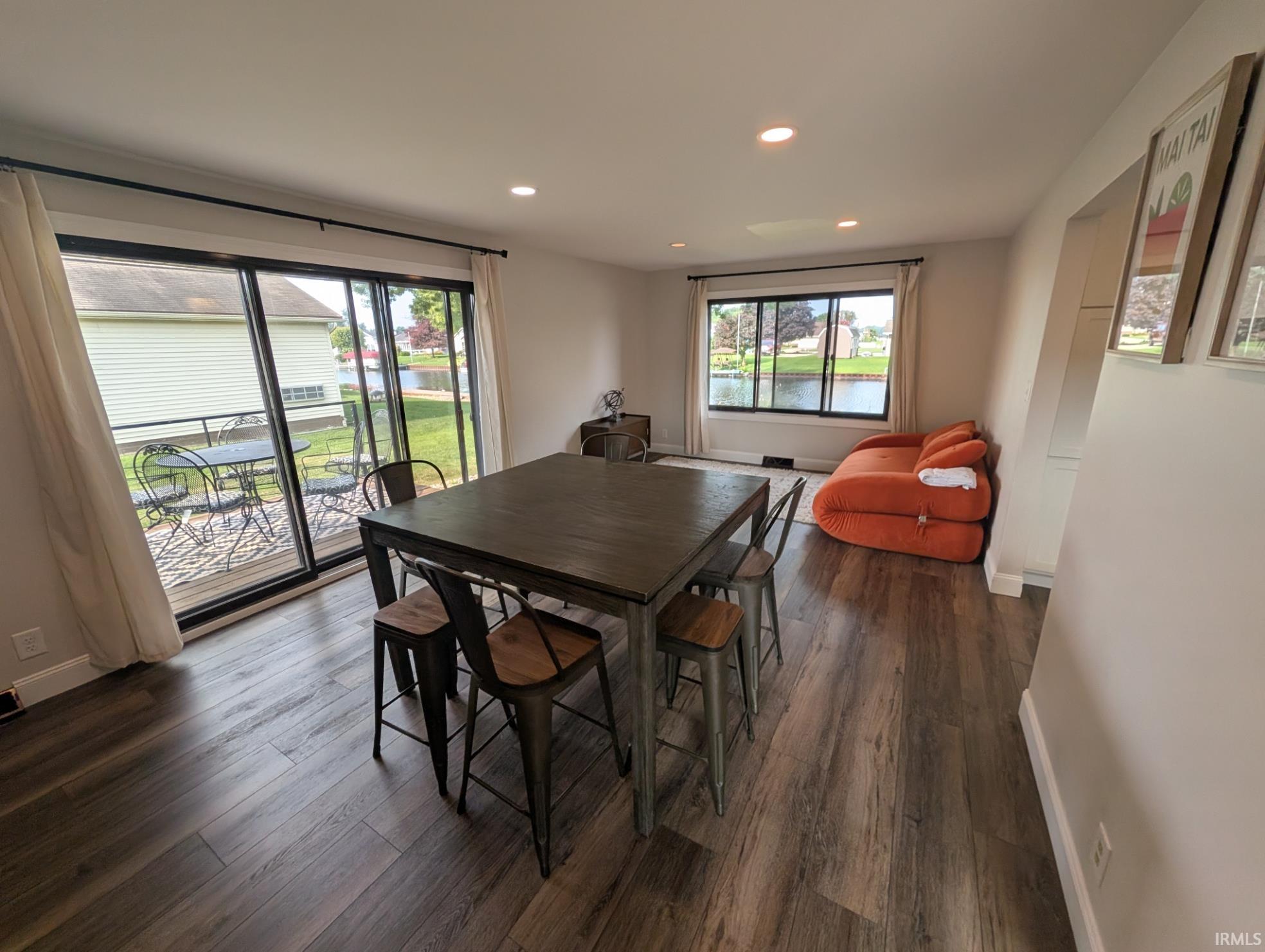 Living area with wood-finish flooring, recessed lighting, and a sliding glass door opening to an outdoor deck