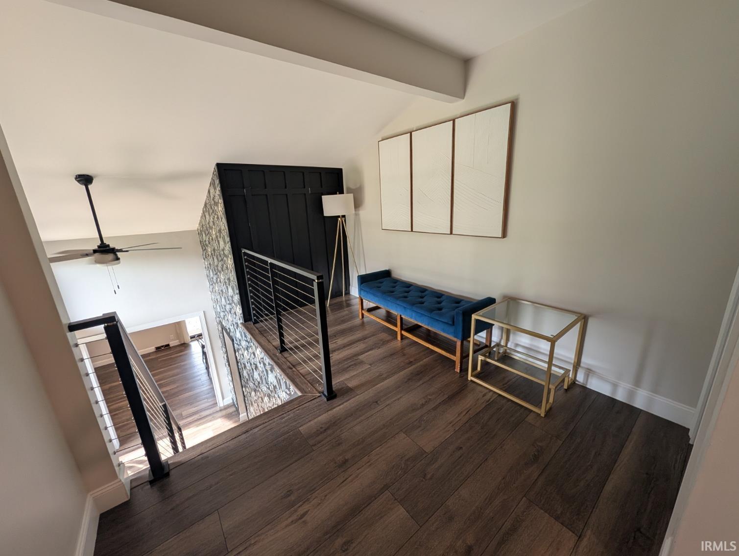 Open-concept landing area featuring wood-finish flooring, a contemporary black and stainless steel wire railing, and a vaulted ceiling with a ceiling fan