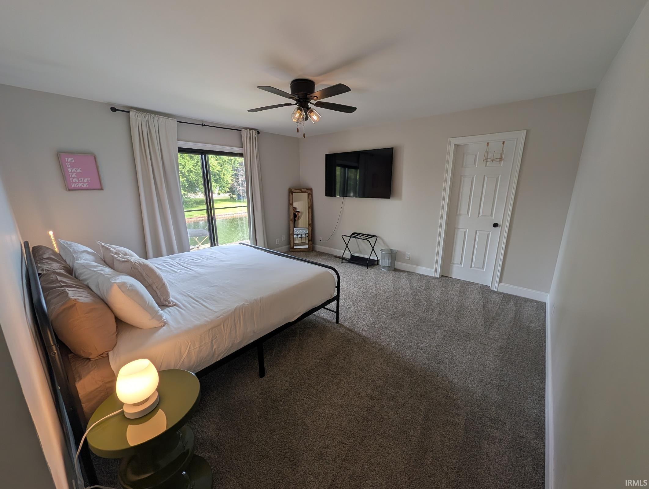 Bedroom featuring light gray walls, dark gray carpet flooring, and a ceiling fan with integrated lighting