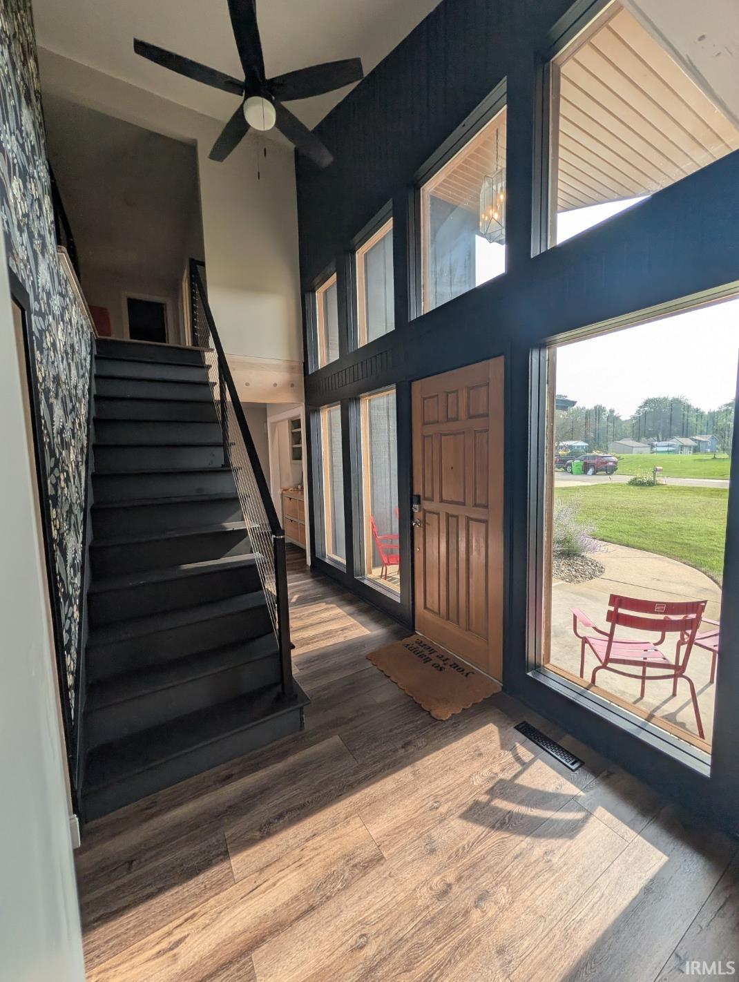Two-story foyer featuring wood-finish flooring and a wood-panel entry door