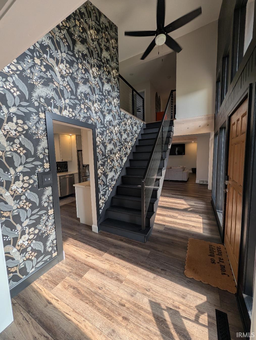 Entry foyer featuring wood-finish flooring and a striking accent wall with botanical wallpaper