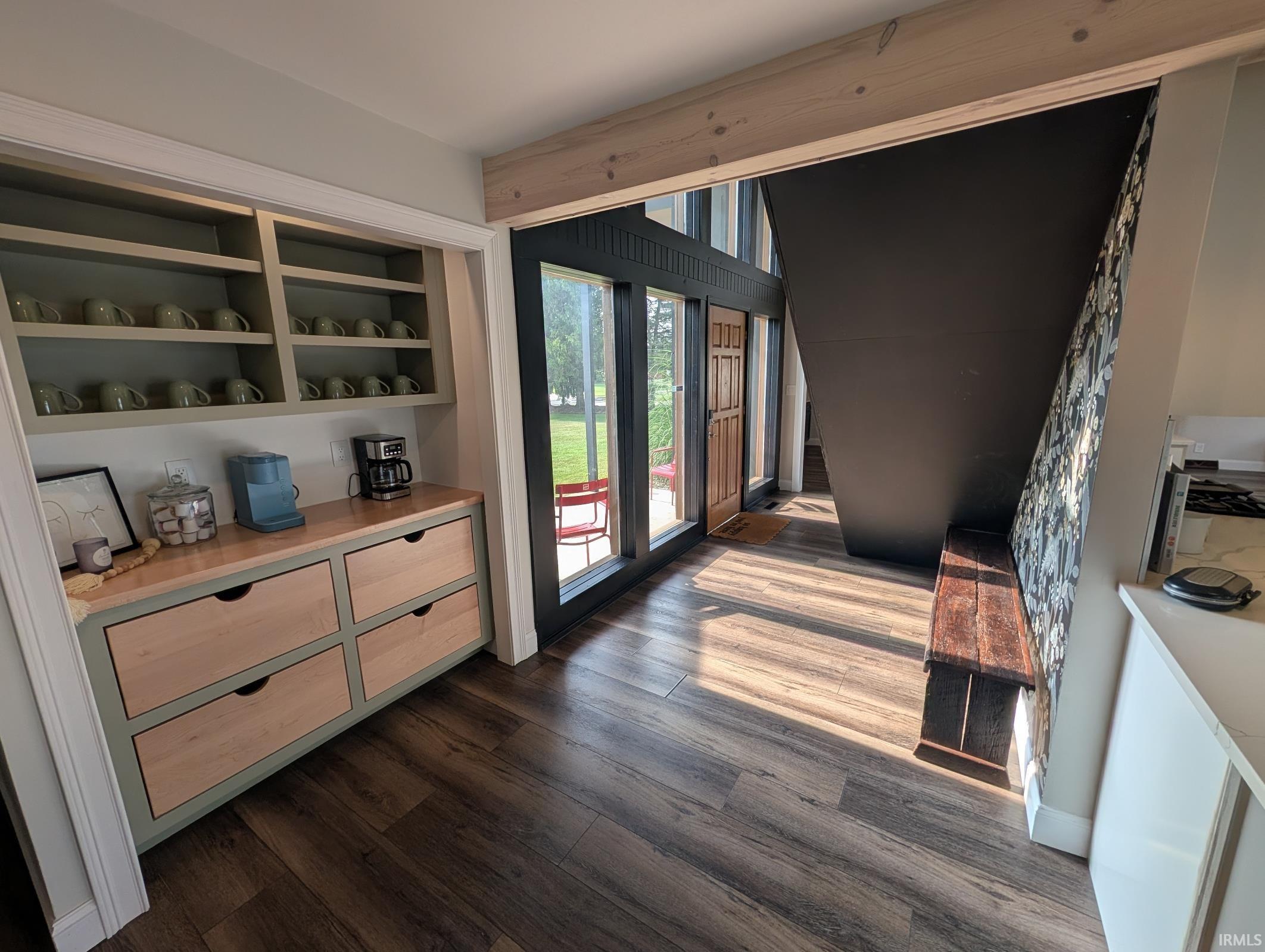 Entryway featuring wood-finish flooring, built-in shelving with lower drawers, a dark-toned staircase, and a wooden bench