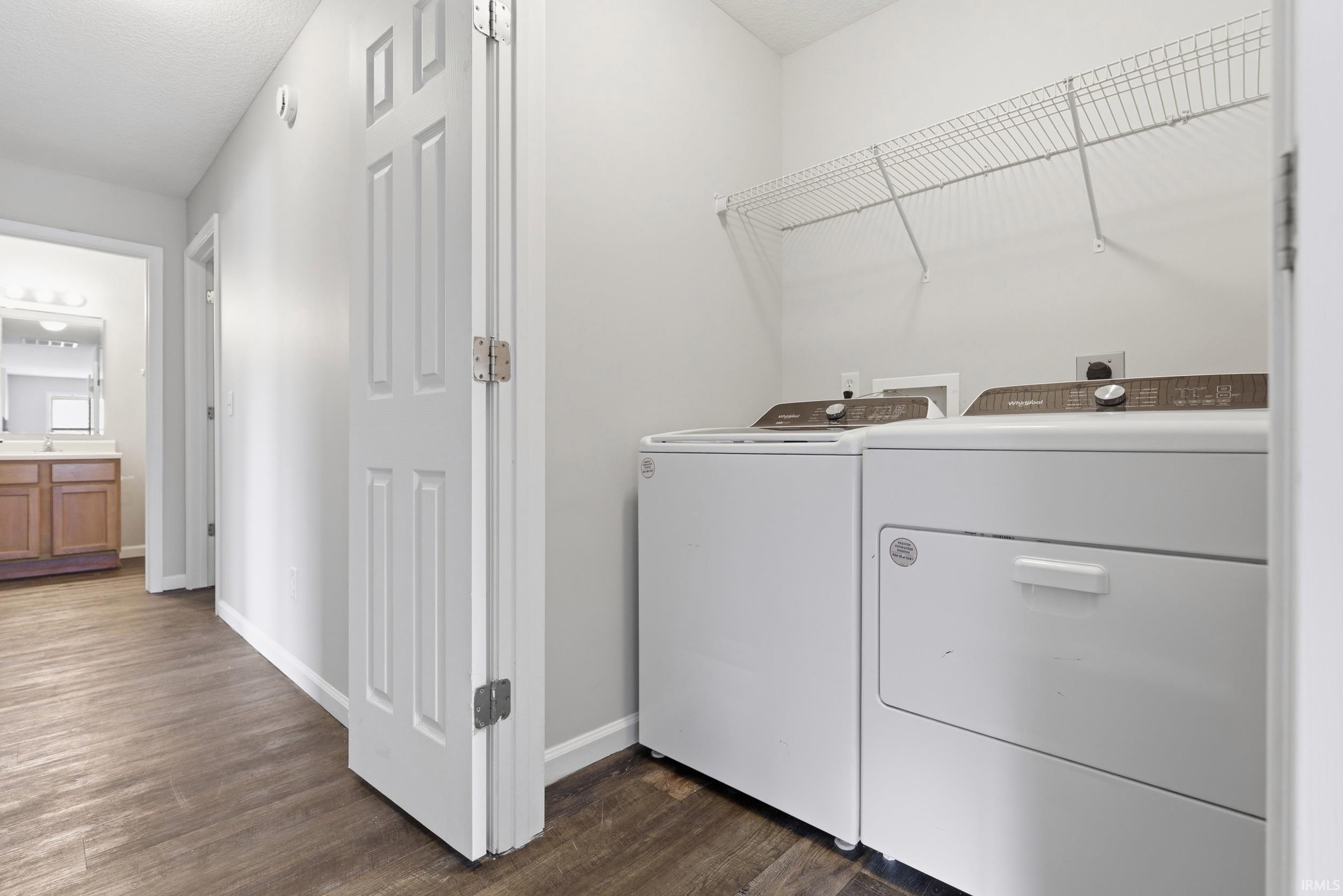 Dedicated laundry area featuring a washer and dryer, wire shelving, and wood-finish flooring