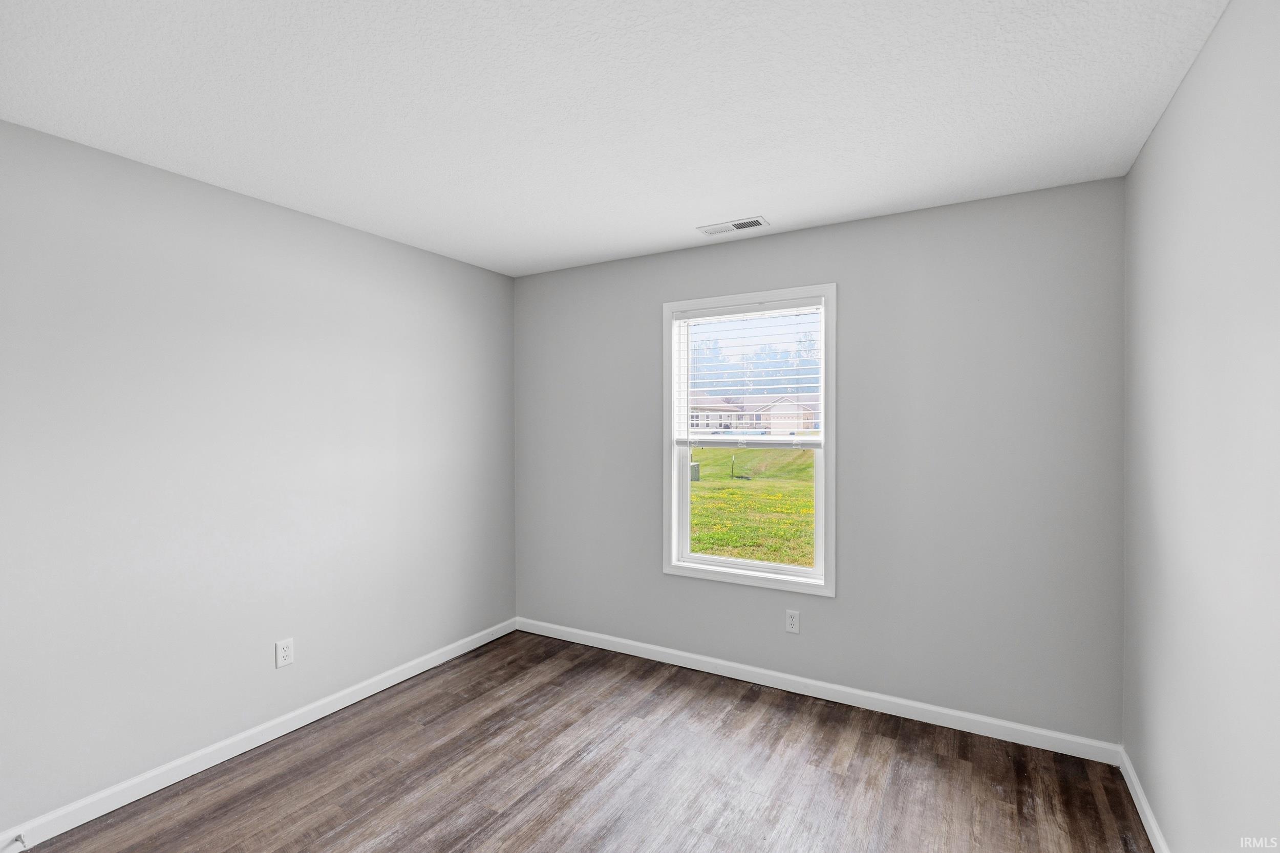 Room featuring wood-finish flooring, light gray walls, white trim, and a white-framed window with blinds