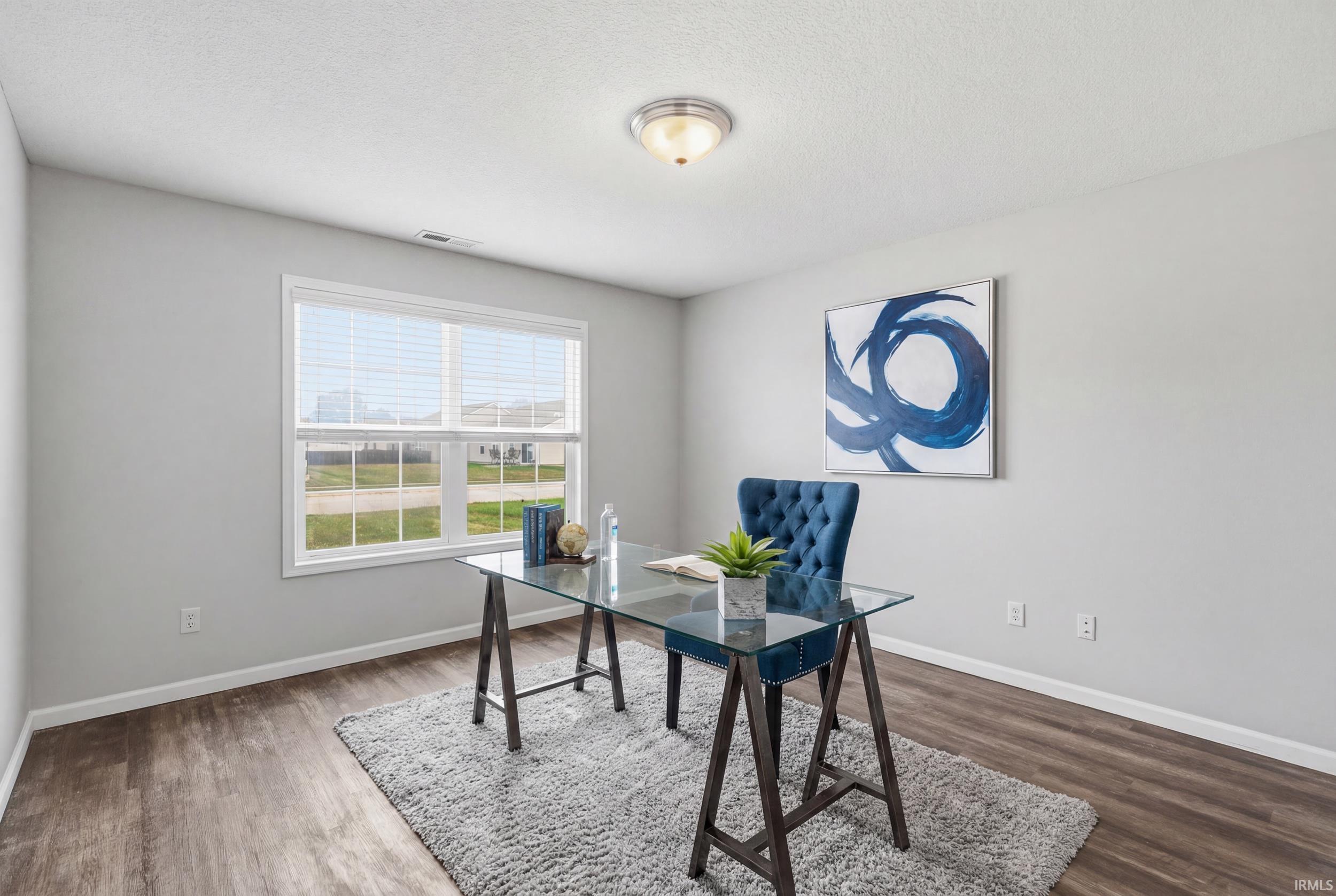Bright interior with wood-finish flooring and a large window featuring blinds