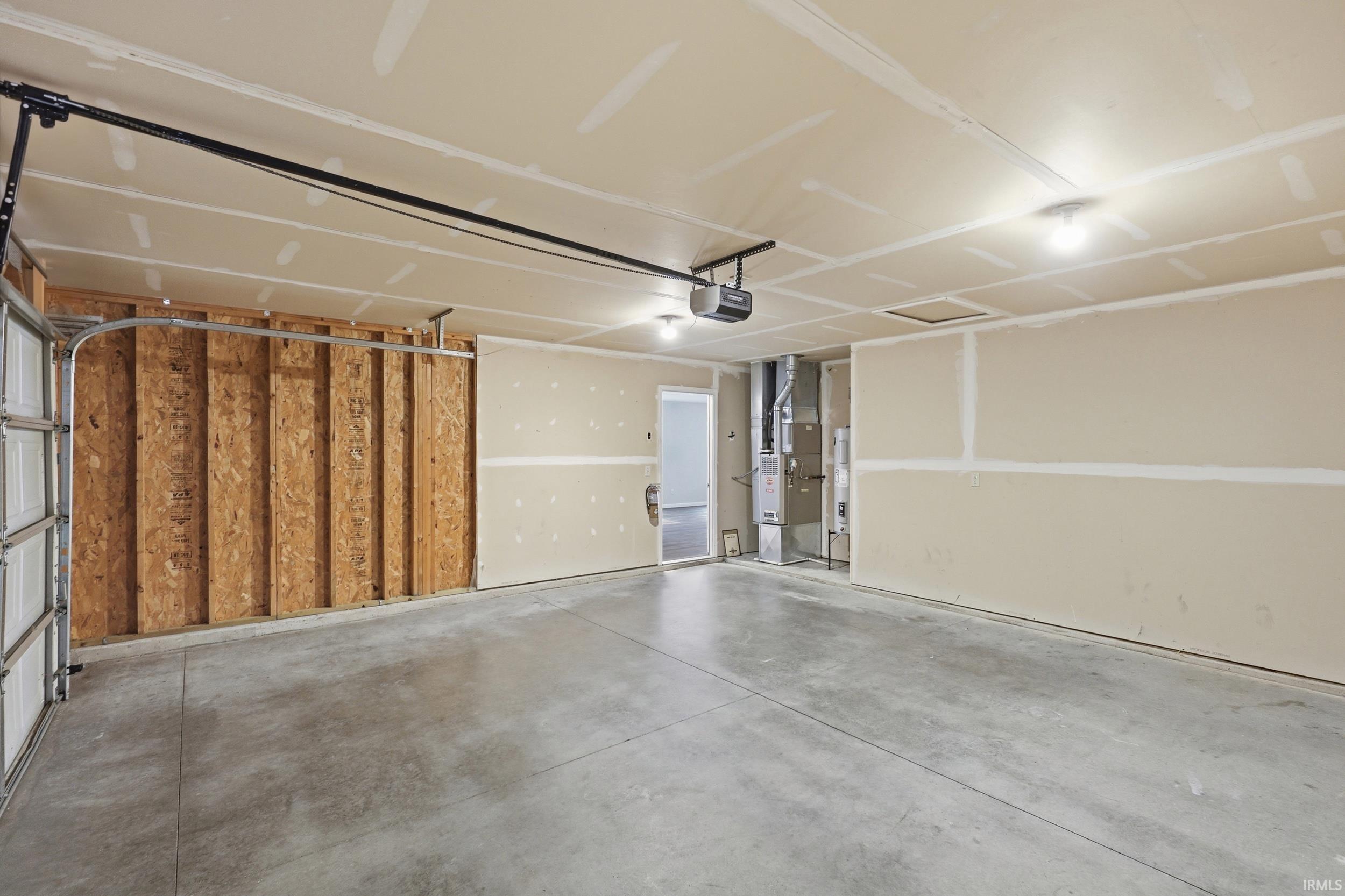 Spacious garage featuring a concrete floor, exposed wood framing, and an automatic garage door opener