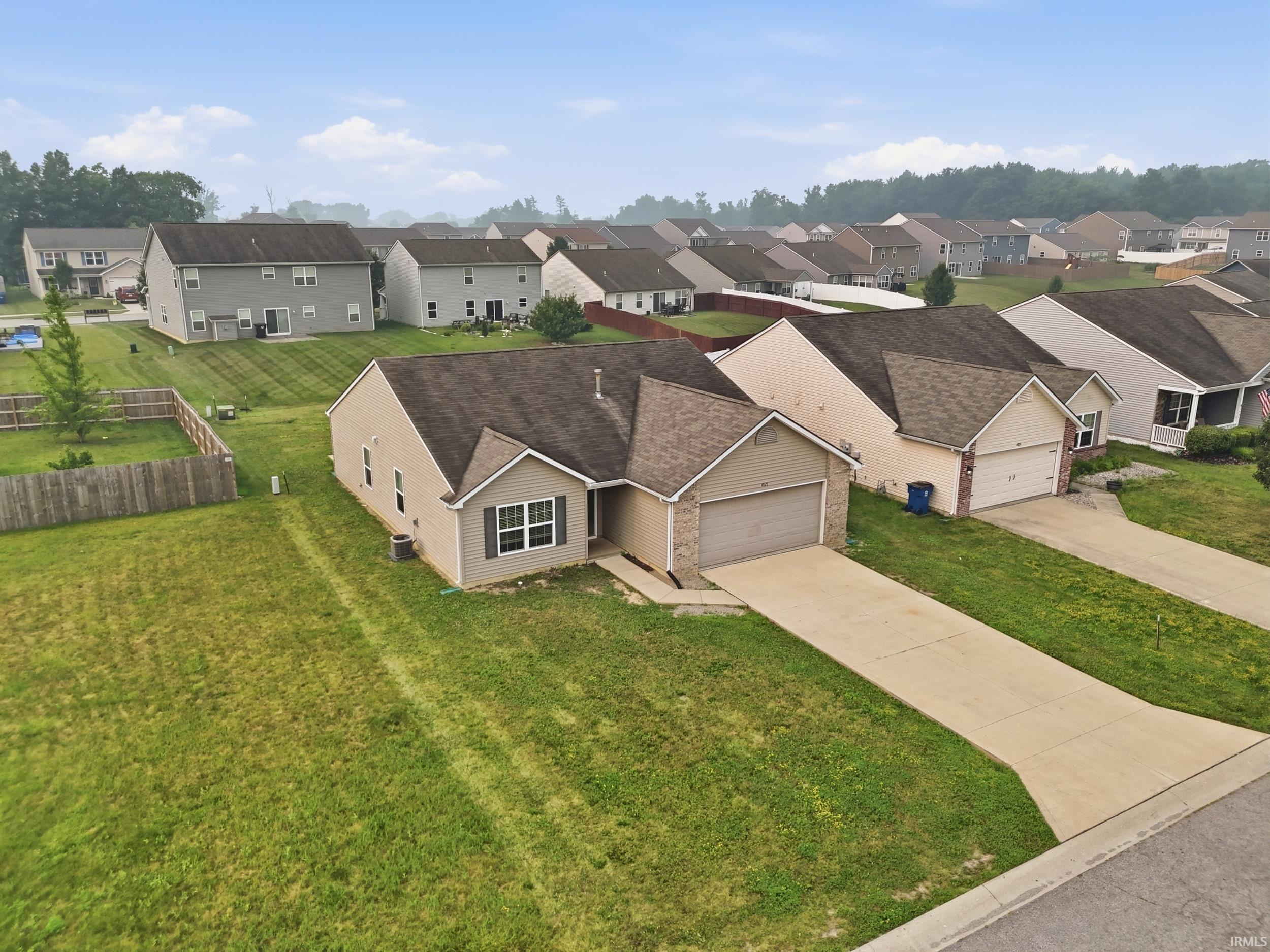 Single-story residence featuring a two-car garage, concrete driveway, and a fenced backyard
