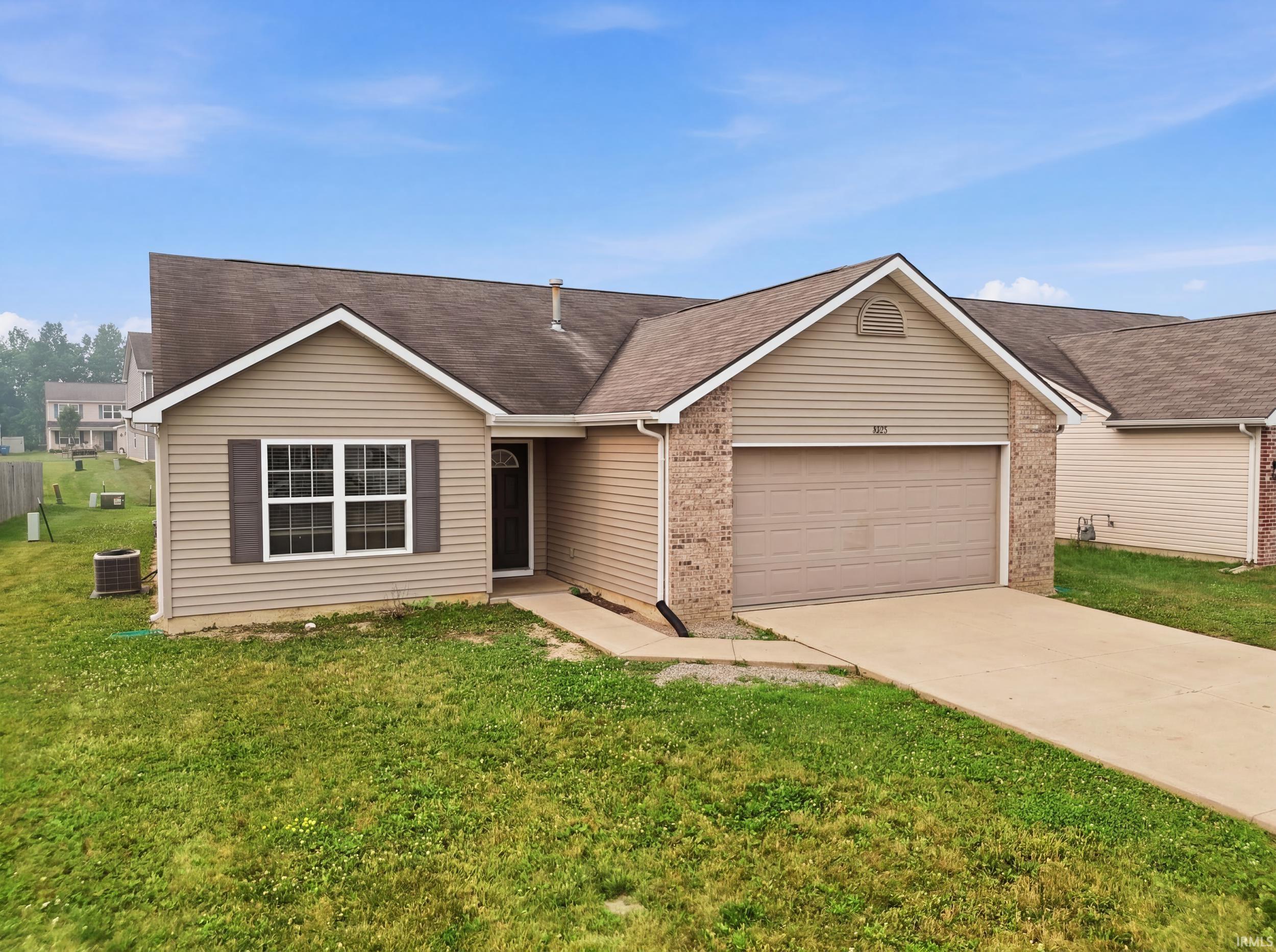 Ranch-style exterior featuring a two-car garage, brick accents, and neutral-toned siding