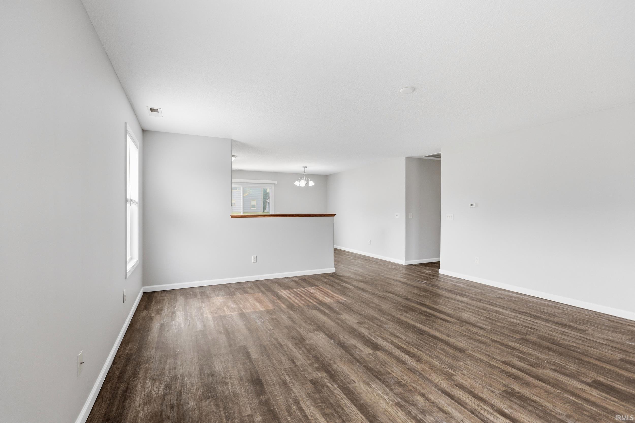 Open-concept living space featuring wood-finish flooring, white baseboards, and light gray walls