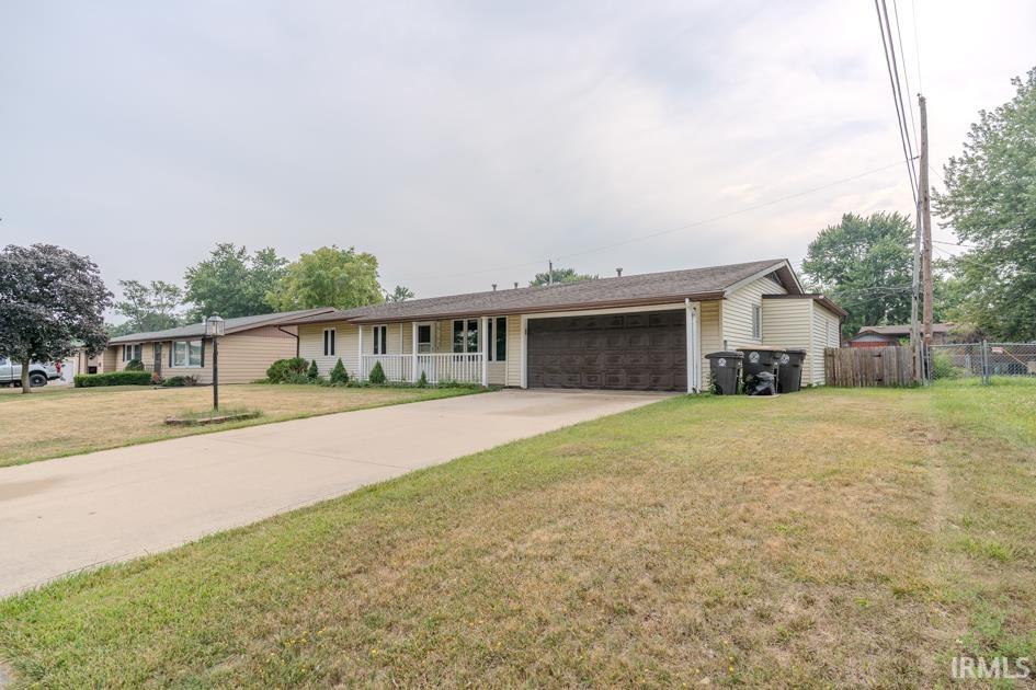 Ranch-style residence featuring a two-car attached garage, light-colored siding, and a covered front porch with white railings