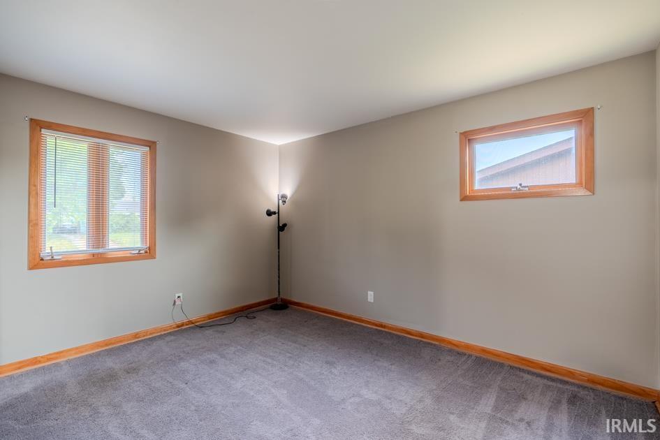 Carpeted room featuring two windows with wood trim