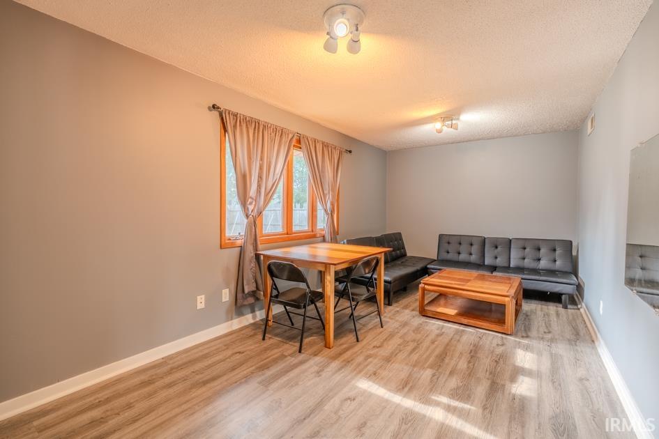 Spacious interior featuring light gray walls, wood-finish flooring, and multiple ceiling-mounted light fixtures