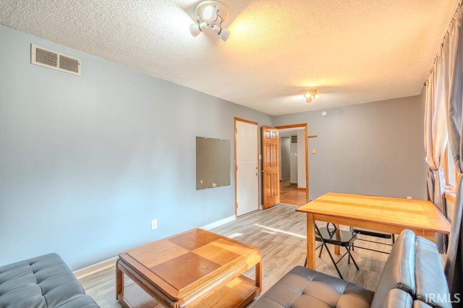 Living area featuring wood-finish flooring, light blue and gray painted walls, and overhead lighting