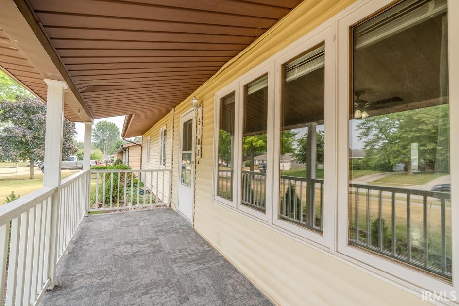 Covered front porch featuring cream siding, white railing, and a textured gray floor