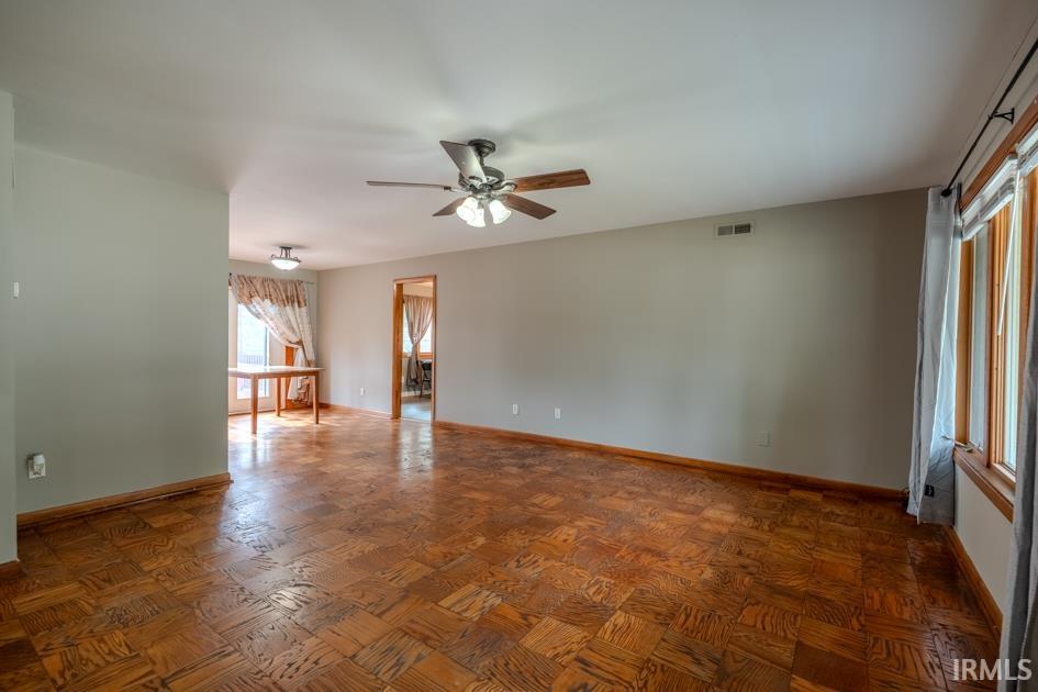 Expansive living area featuring parquet wood flooring and a ceiling fan with integrated lighting