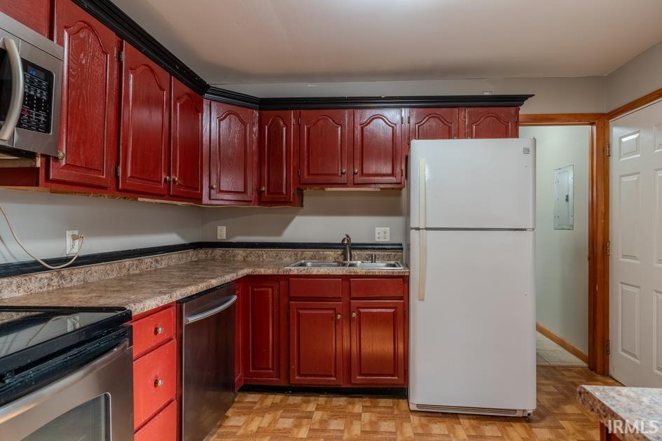 Kitchen featuring red wood-finish cabinetry with black crown molding, laminate countertops, and wood-look flooring