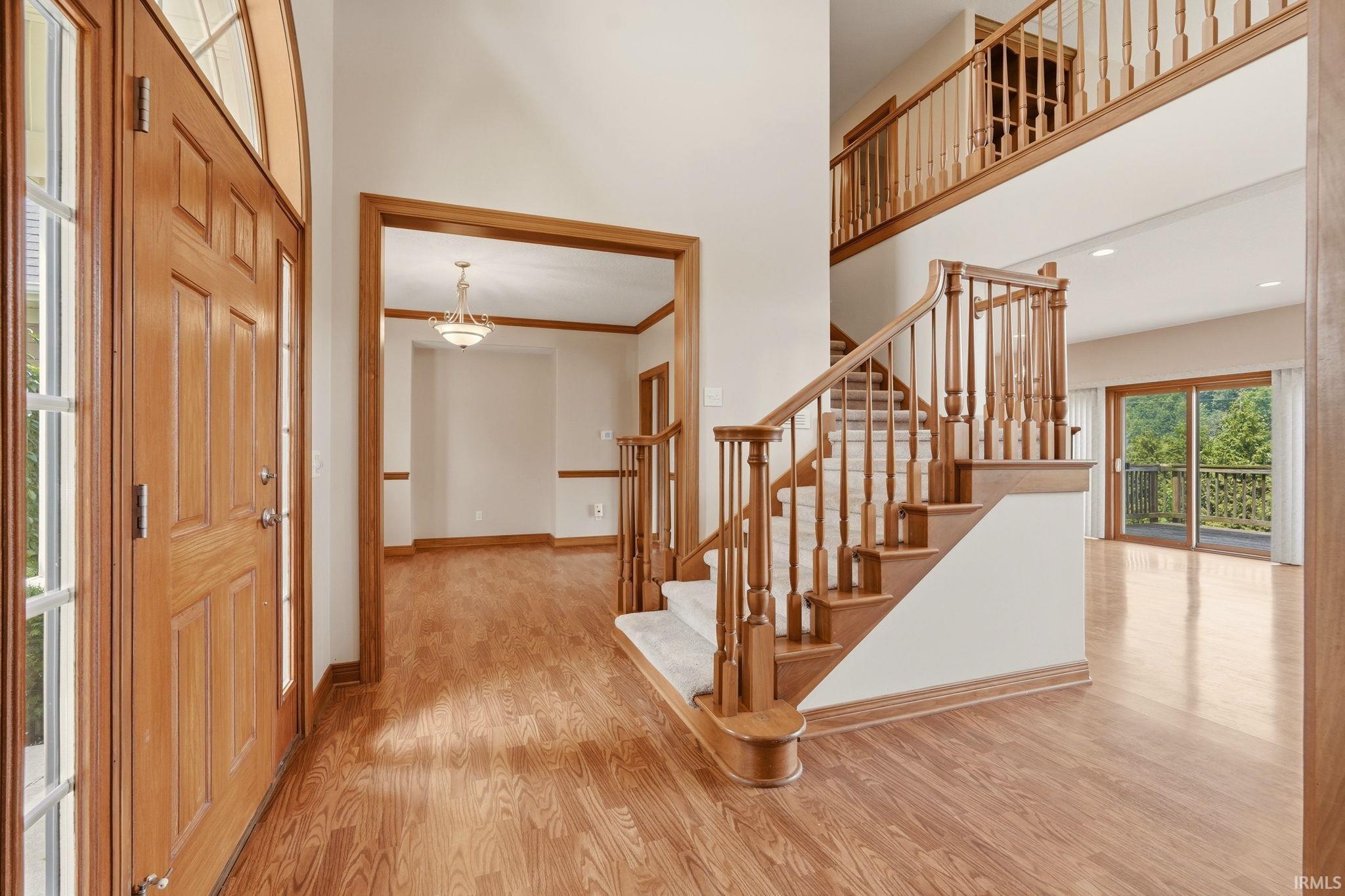 Two-story foyer with a natural wood front entry door featuring side windows and an arched transom
