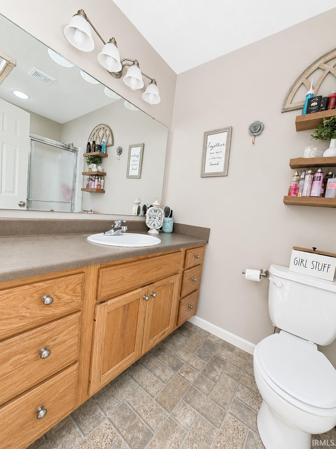 Bathroom featuring an oak-finish vanity with a single sink and gray countertop