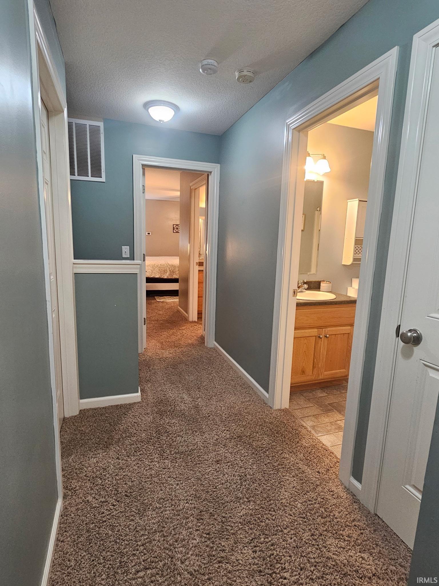 Carpeted hallway with light blue walls and white trim