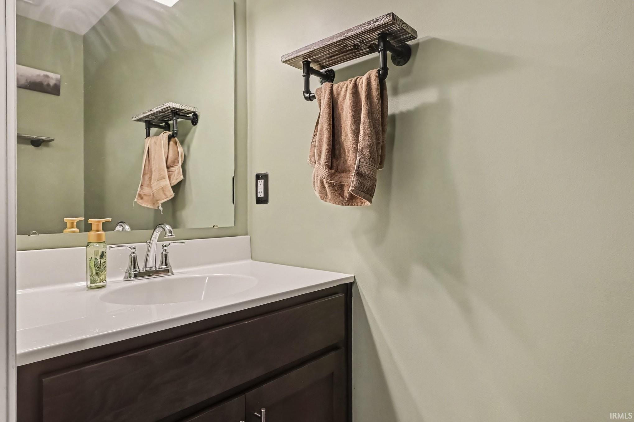 Bathroom vanity with a white countertop and integrated sink, chrome faucet, and dark wood-finish cabinetry
