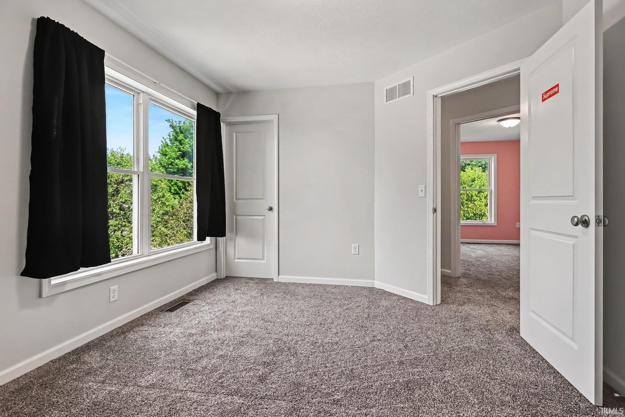 Carpeted room featuring light gray walls, white trim, and a window with white framing