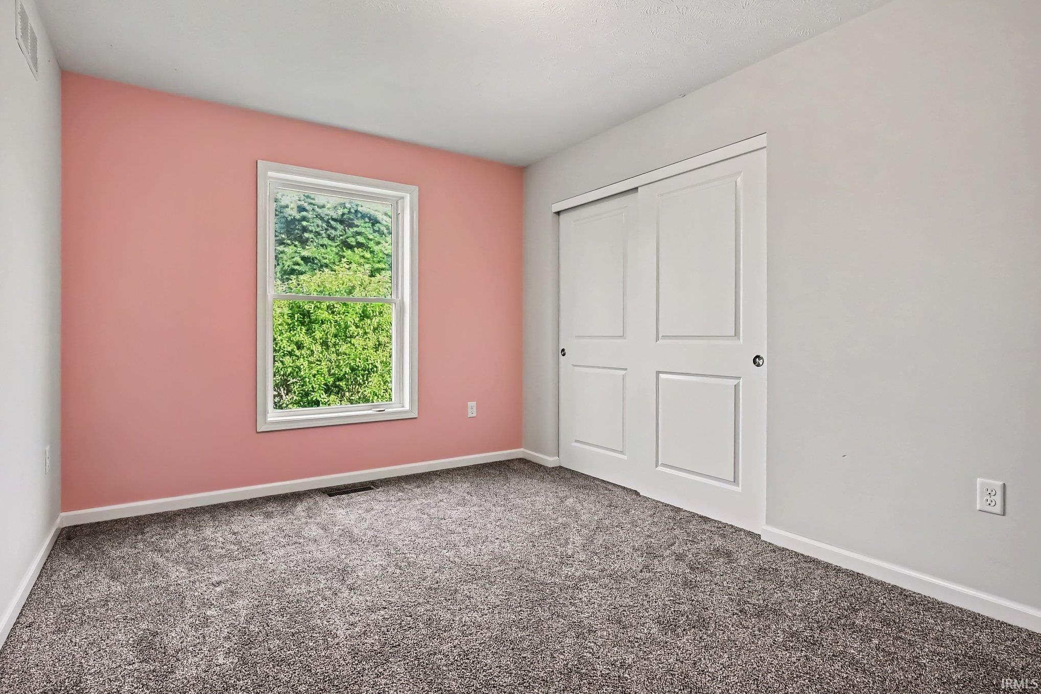 Room featuring light gray walls and one accent wall in a soft pink hue