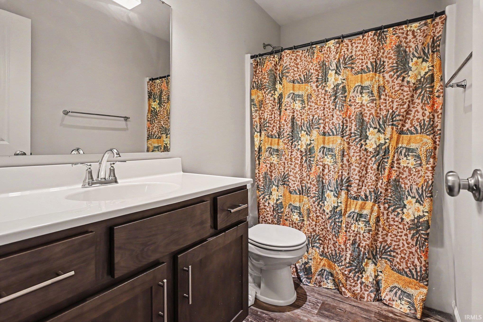 Bathroom featuring a dark wood-finish vanity with a white countertop and integrated sink, chrome faucet, and mirrored wall