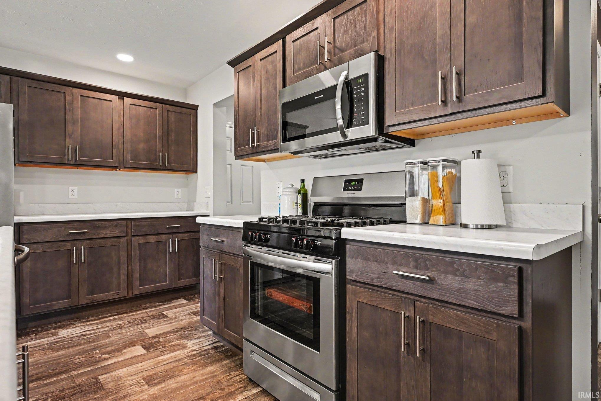Kitchen featuring dark wood-finish cabinetry with silver hardware, light countertops, and a white subway tile backsplash