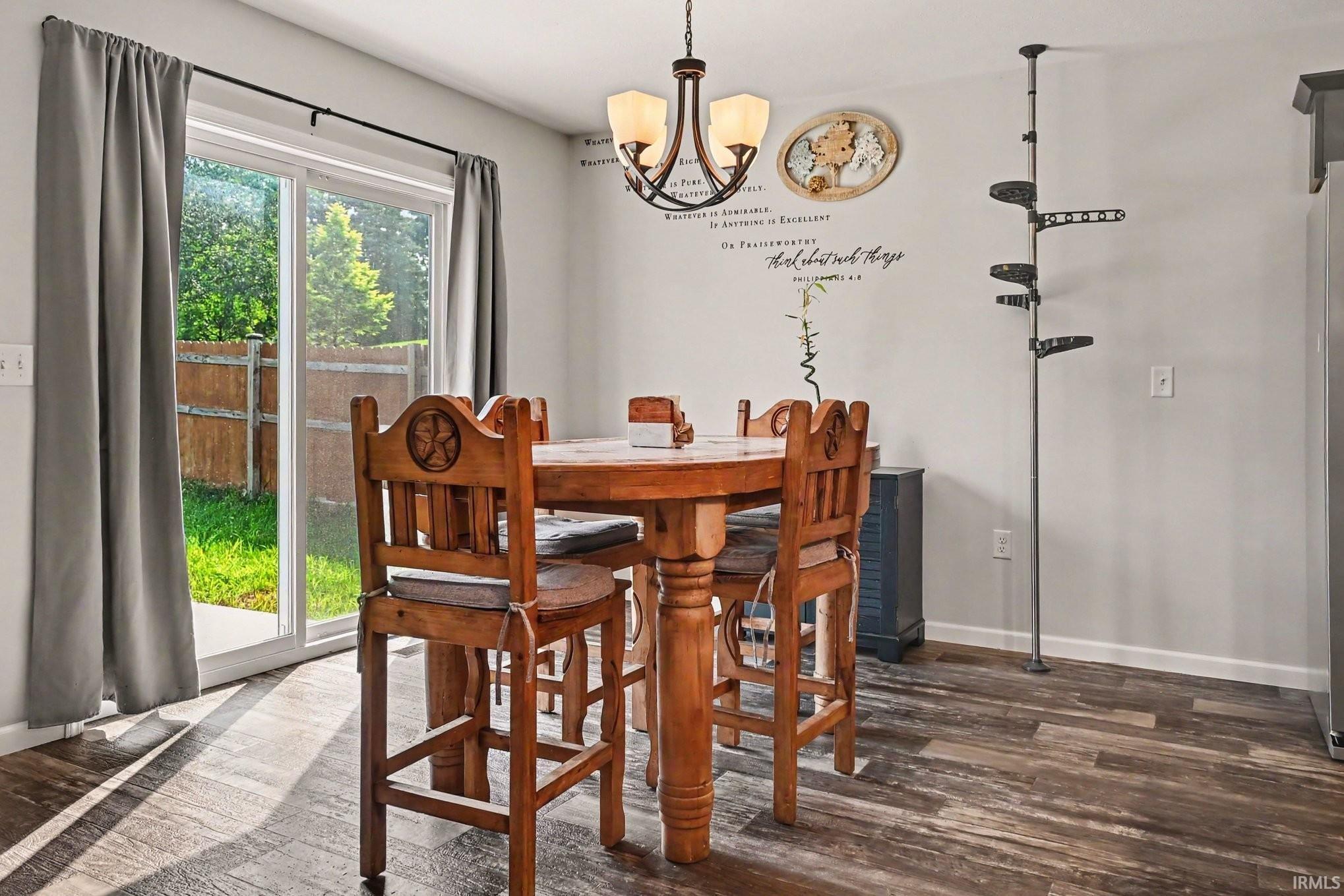 Dining area featuring wood-finish flooring, a contemporary chandelier, and sliding glass doors opening to the exterior